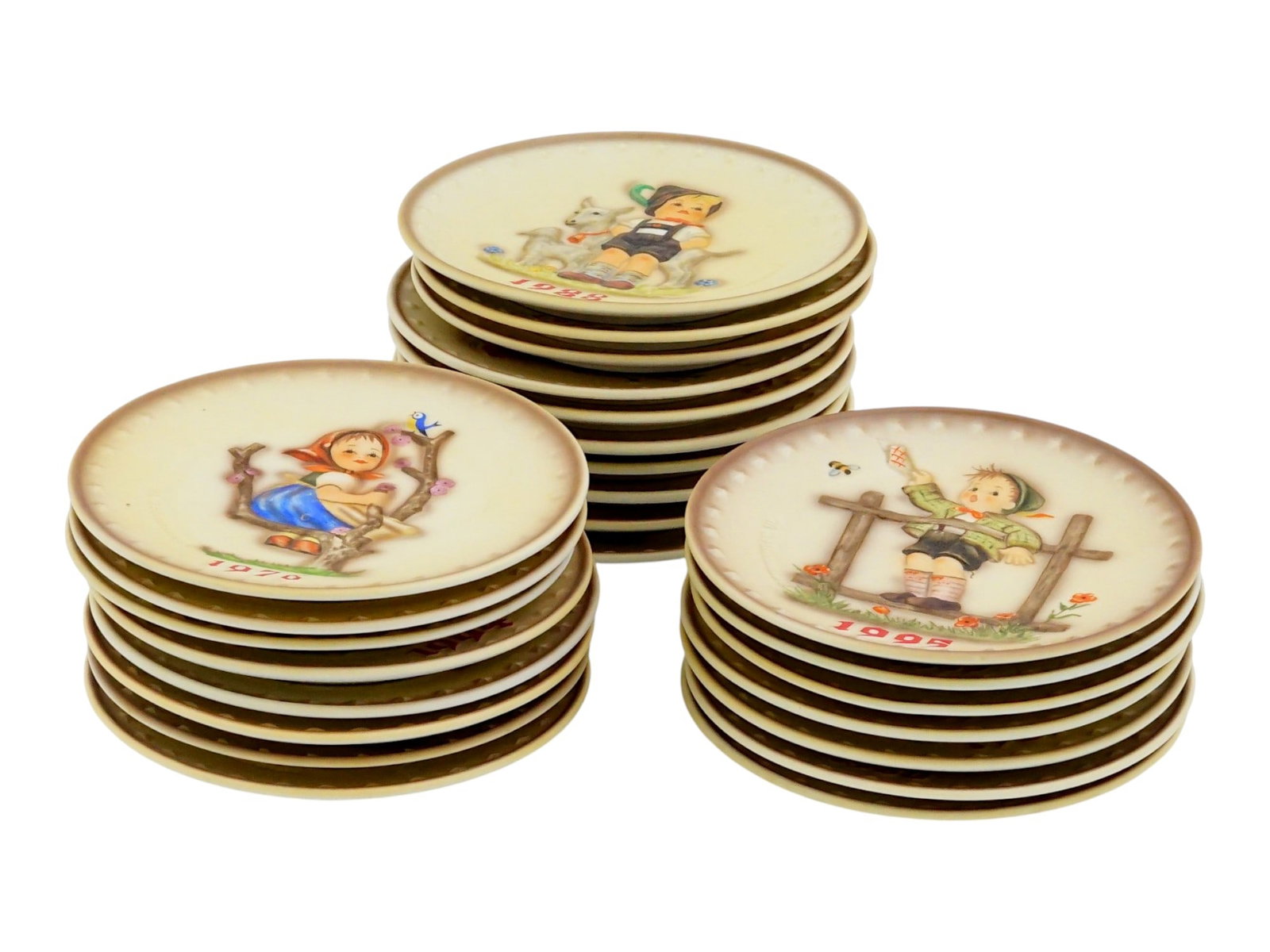 25 ANNUAL GERMAN GOEBEL HUMMEL PORCELAIN PLATES: A vintage collection of 25 annual Goebel Hummel porcelain plates, produced in West Germany between 1971 and 1995. Each plate features a relief design based on illustrations by Sister Maria Innocentia 