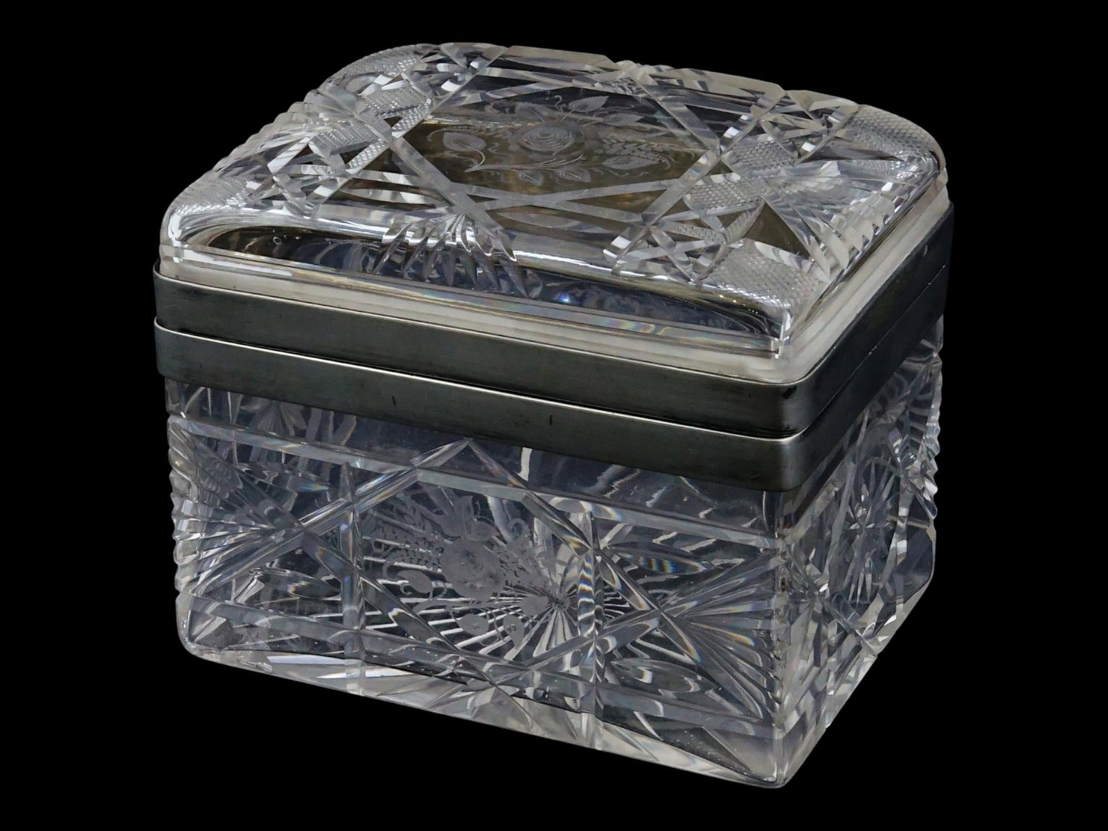 RECTANGULAR SHAPED COVERED CUT CRUSTAL GLASS BOX: A rectangular shaped case crafted from cut crystal glass featuring deep diamond cut patterns to the sides and a radiant starburst design to the underside. The hinged lid is decorated with intricate wh