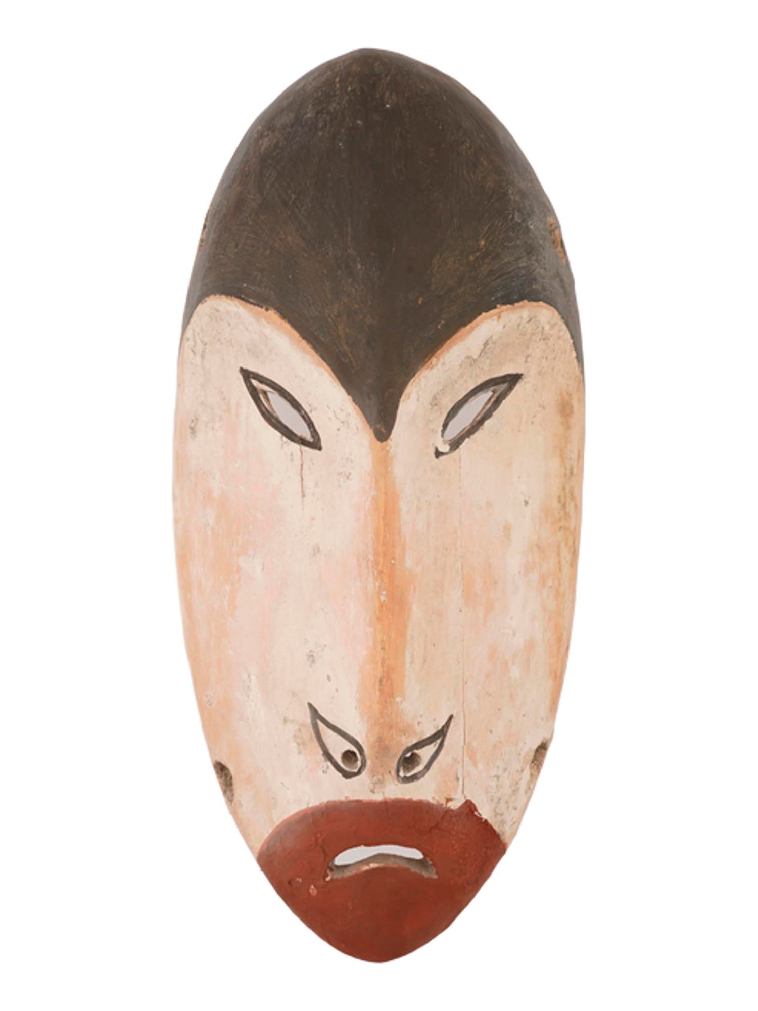 AMERICAN YUPIK CARVED AND PAINTED CEREMONIAL MASK: An American Yupik ceremonial mask, carved from driftwood and painted with natural pigments. Characterized by its elongated, heart-shaped face and white surface, the mask embodies spiritual symbolism a