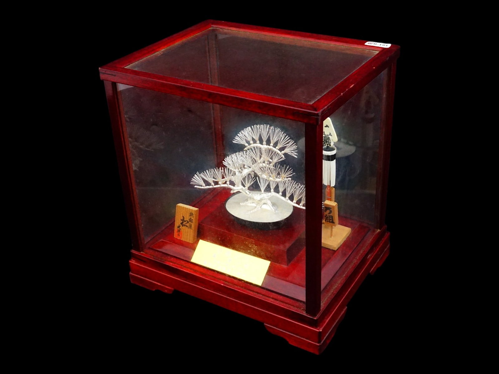 FINE MITSUNORI JAPANESE SOLID SILVER BONSAI TREE: A Japanese solid silver decorative bonsai pine tree produced by Mitsunori. Dated ca. 1999. The piece is mounted in a wooden display case which also features signs with good wishes and a title plaque. 