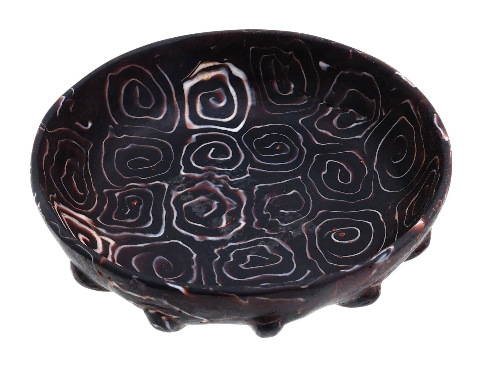 ANCIENT ROMAN EMPIRE GLASS MOSAIC RIBBED BOWL: An Ancient Roman glass mosaic ribbed bowl. Roman Empire era, ca. 1st century AD. Translucent deep purple ground color and opaque white swirl design reminiscent of modern millefiori glass. Ribbed bowls