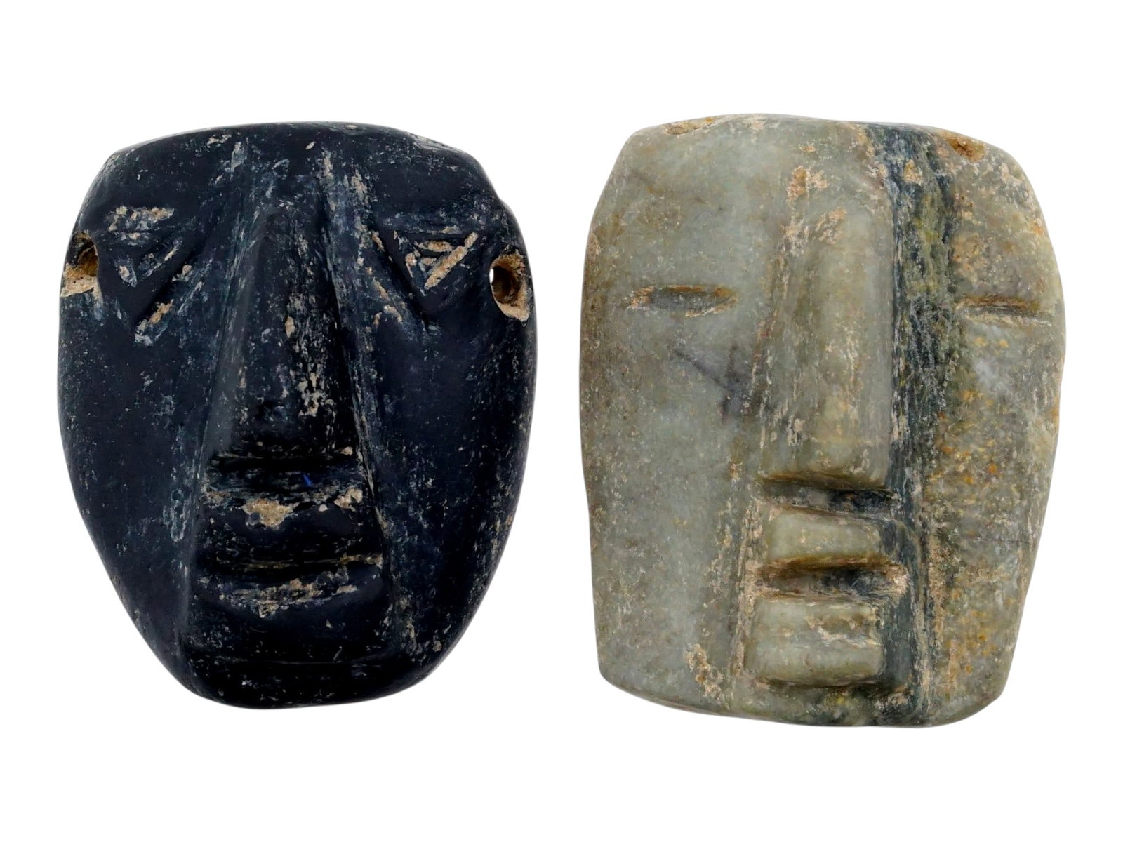 ANCIENT PRE COLUMBIAN OBSIDIAN AND JADE PENDANTS: A lot of two ancient Pre Columbian hand-carved obsidian and jade stone face pendants. Both pendants feature a stylized human face with distinct features: full lips and a wide nose and have drilled hol