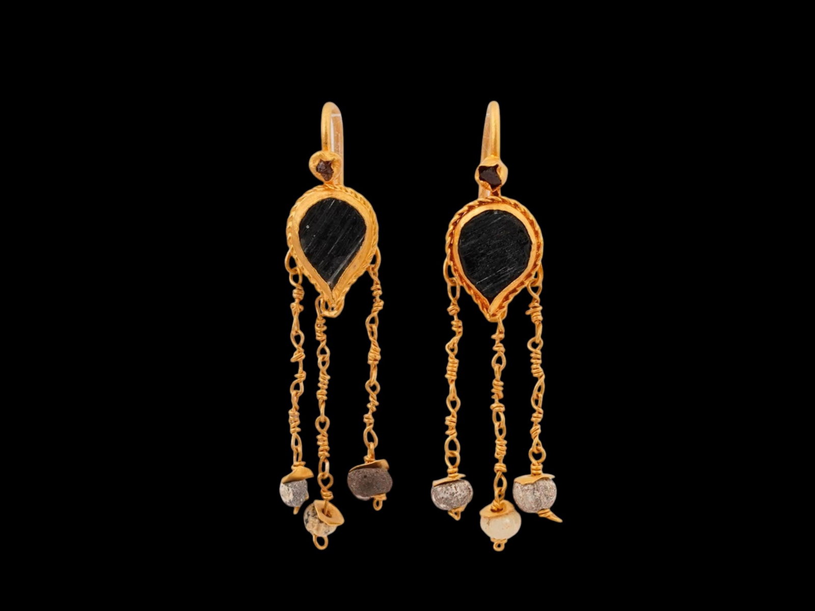 ANCIENT ROMAN GOLD AND GLASS EARRINGS WITH DANGLES: An ancient Roman gold and glass earrings, dating from 100 to 300 AD. Each earring features a central drop-shaped glass element with three dangling gold chains, each with delicate beads. Ancient Roman 