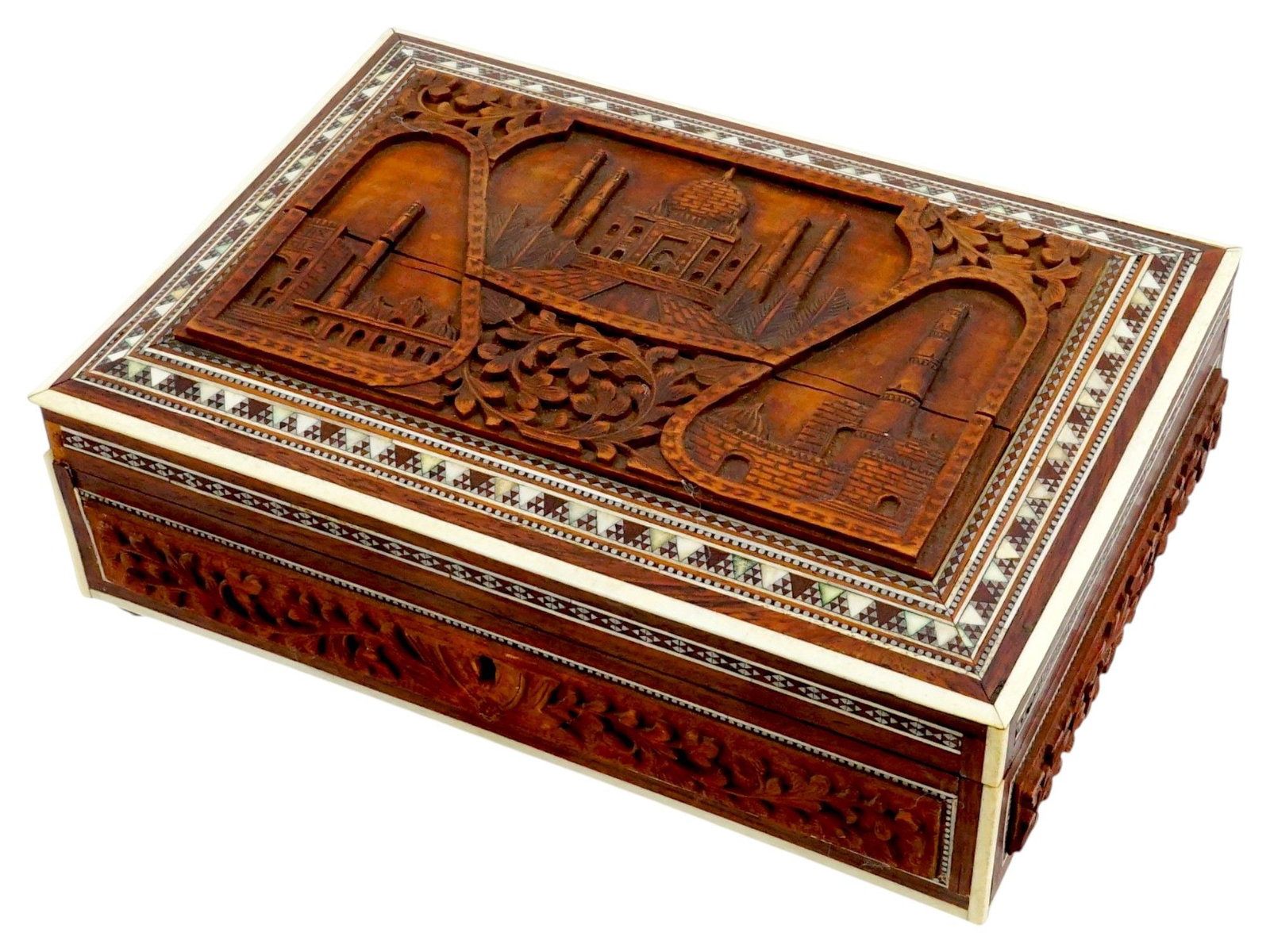 VINTAGE INDIAN CARVED WOODEN INLAY BOX TAJ MAHAL: A vintage Indian wooden trinket box. Ca. 1950s. Brass fittings and feet. Key lock. The hinged lid is embellished with intricate ornamental inlay and hand-carved view of Taj Mahal. The side are also de