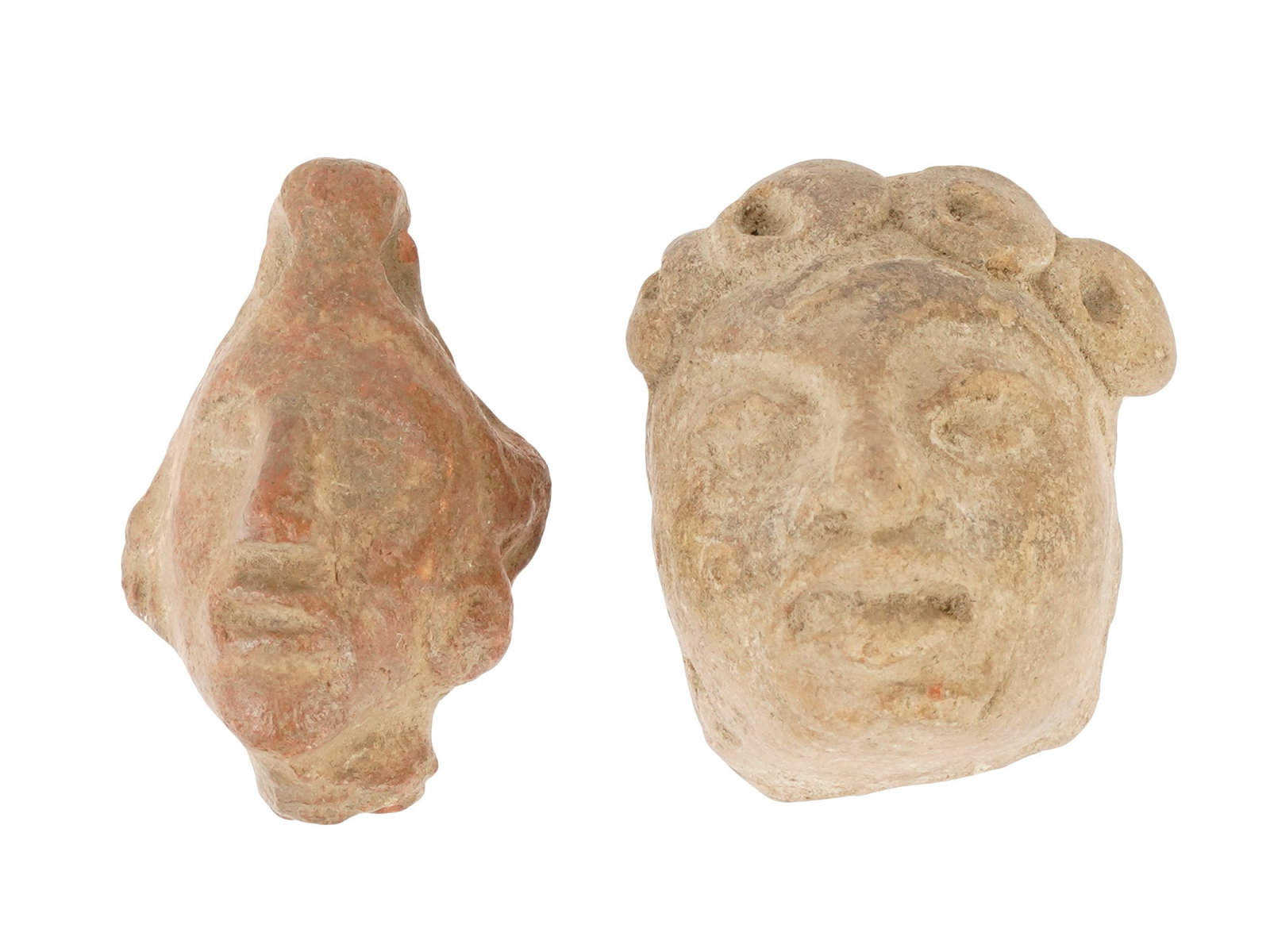 PAIR OF MINIATURE ANTIQUE OR ANCIENT CARVED STONE HEADS: A pair of miniature antique or ancient hand-carved stone heads. The heads are of varying shapes, with different facial features and hairstyles, and with traces of paint on the surface. One of the two 