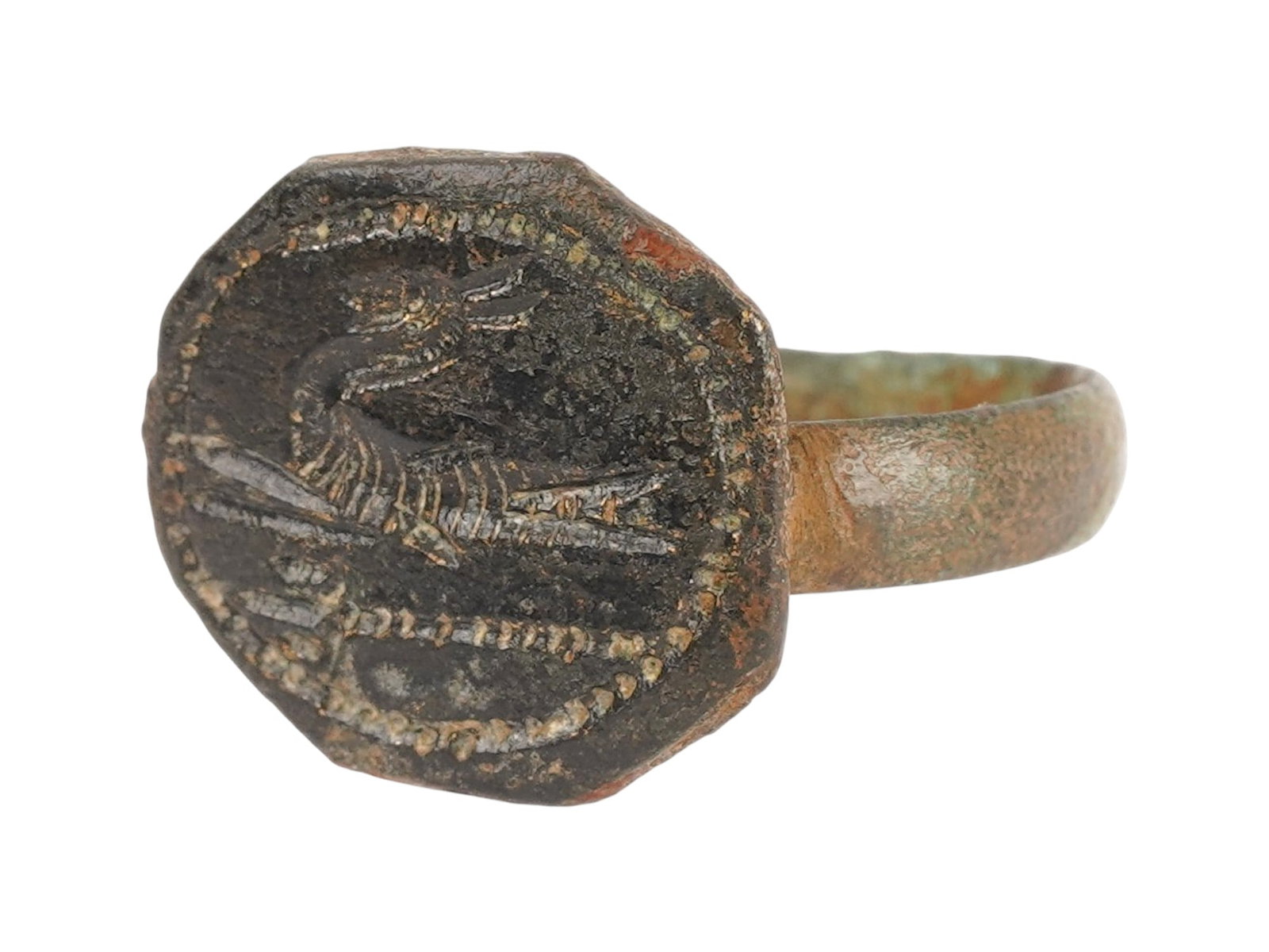 ANCIENT GRECO ROMAN BRONZE SIGNET RING 200 BC TO 100 AD: An ancient Greco Roman bronze signet ring features a prominent, flattened circular bezel. Circa 200 BC to 100 AD. The intaglio decoration depicts a long-necked mythological bird. The bezel is supporte