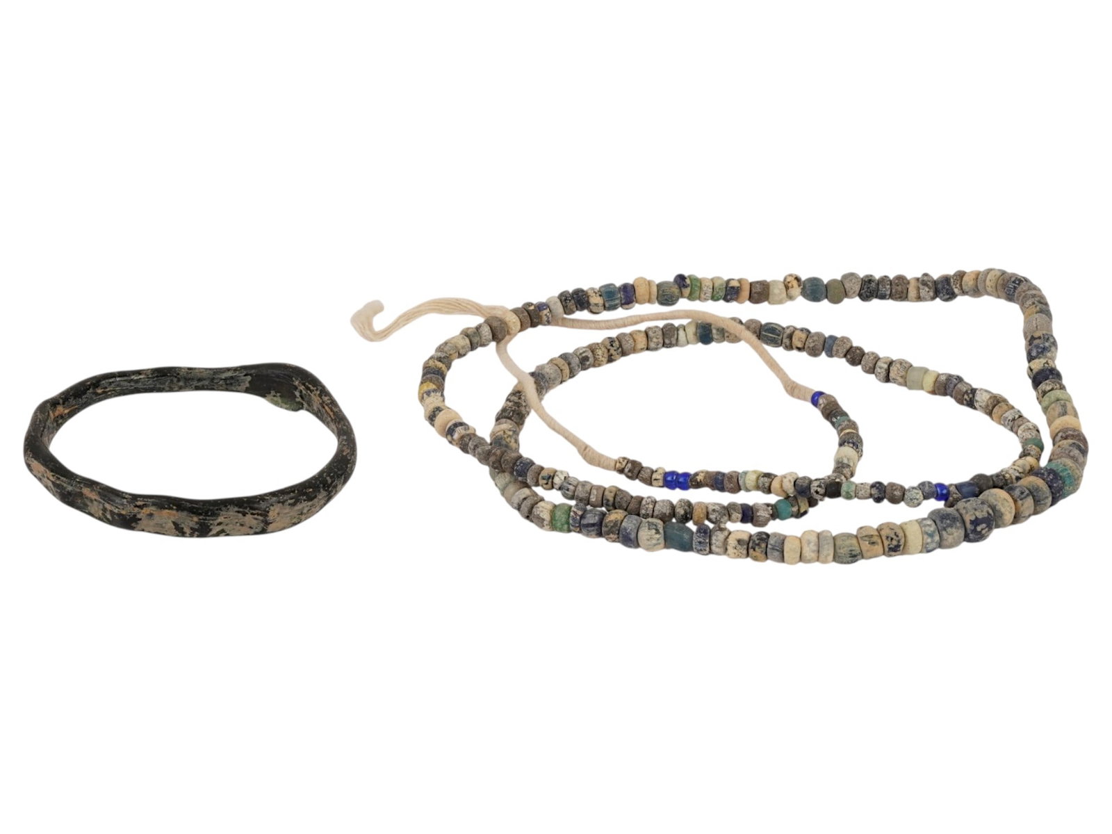ANCIENT ROMAN GLASS BANGLE BRACELET W BEAD NECKLACE: An ancient Roman glass bangle bracelet with a strand of glass bead necklace, dating circa 100 to 300 AD. The bracelet is fashioned from a single loop of dark, nearly opaque glass. The accompanying nec