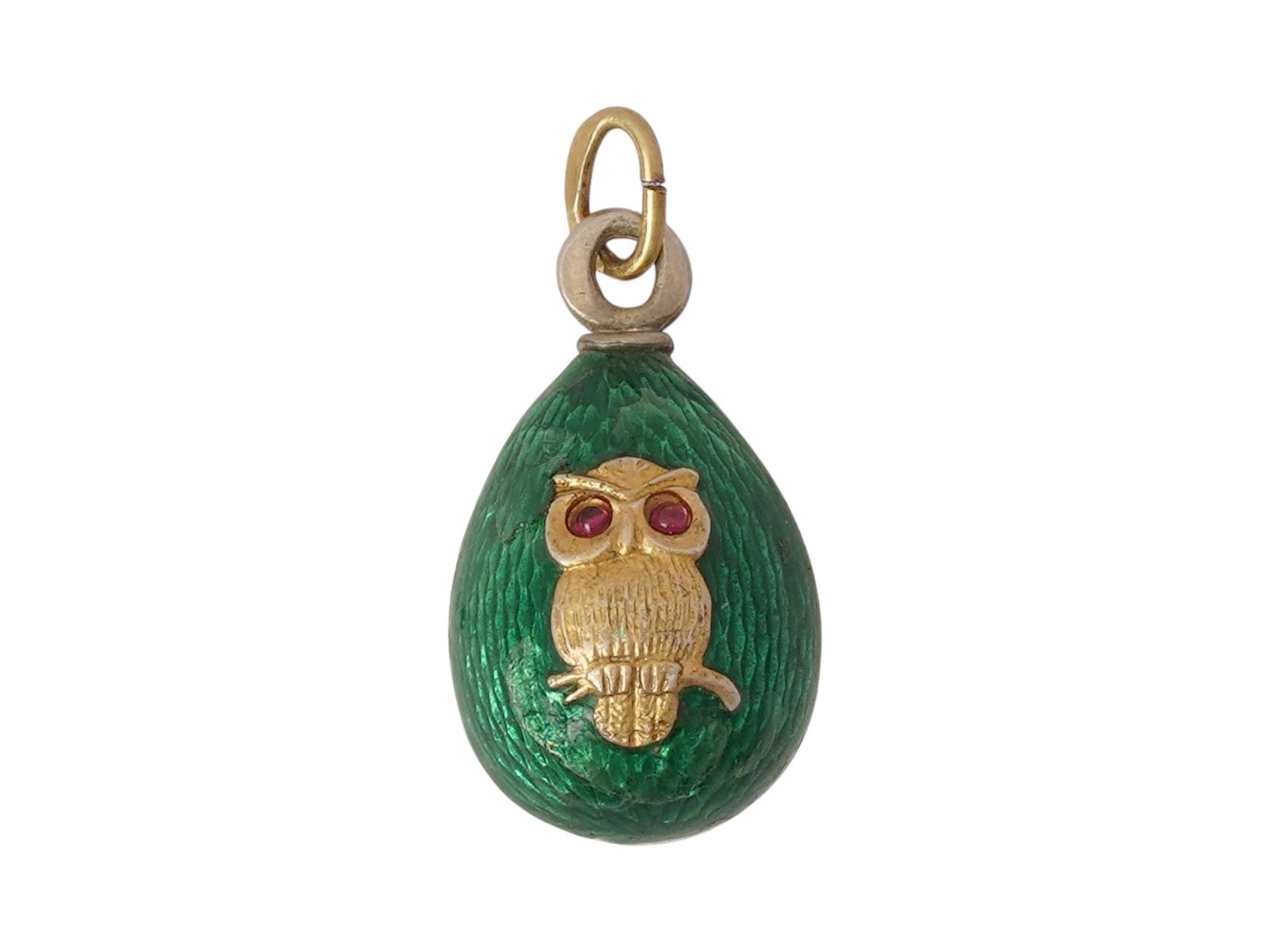 RUSSIAN SILVER GUILLOCHE ENAMEL EASTER EGG PENDANT: A Russian gilt Silver and enamel Easter egg pendant. The exterior of the egg is covered with Guilloche enamel in a green shade and adorned with a relief design representing an owl, encrusted with Ruby