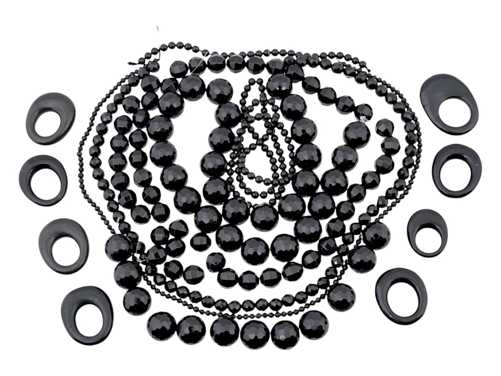 COLLECTION OF ASSORTED CARVED ONYX BEADS STRINGS: A collection of strings with assorted carved black Onyx stone manner beads. The circular shaped beads are made in various sizes. The lot is also completed with oval ring shaped beads. Vintage Jewelry