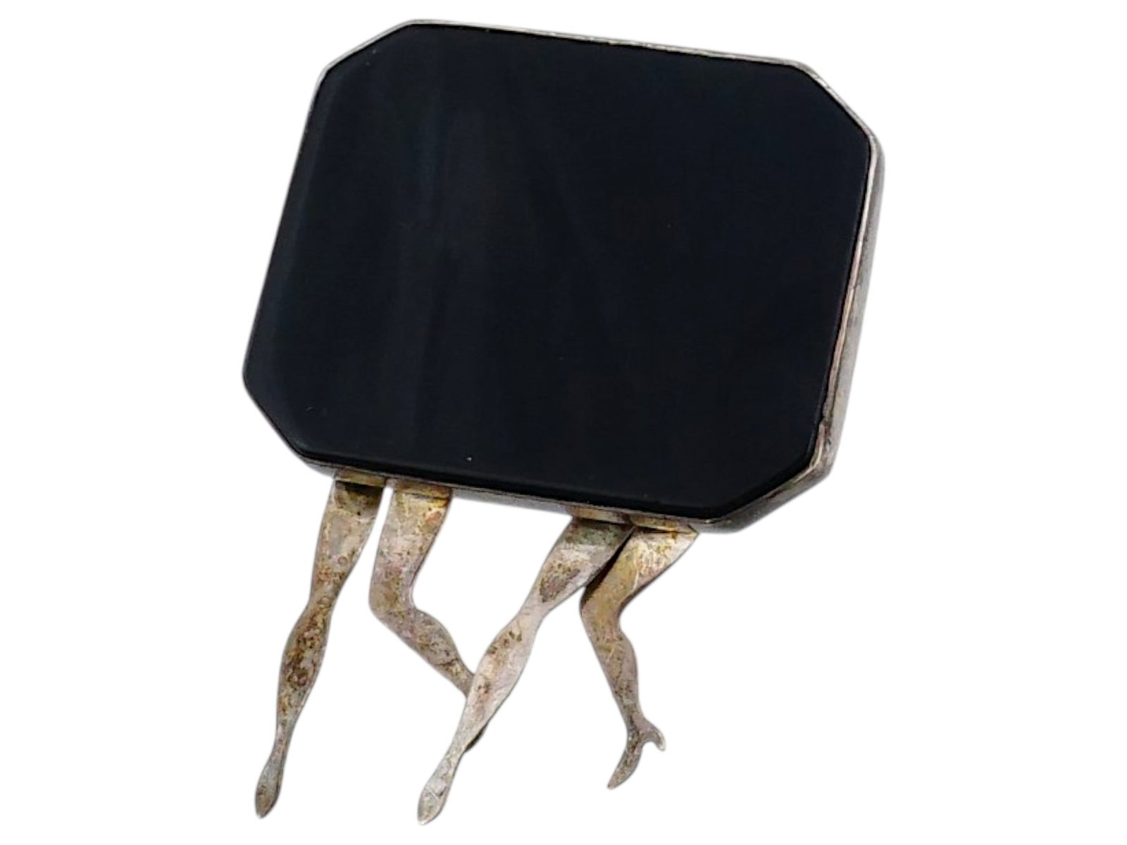 VINTAGE SILVER BLACK ONYX BROOCH WITH DANGLING LEGS: A vintage brooch featuring a rectangular, octagon-cut black onyx stone set in sterling silver, with four dangling human legs underneath. Marked sterling on the back side. Each leg is secured to the ma