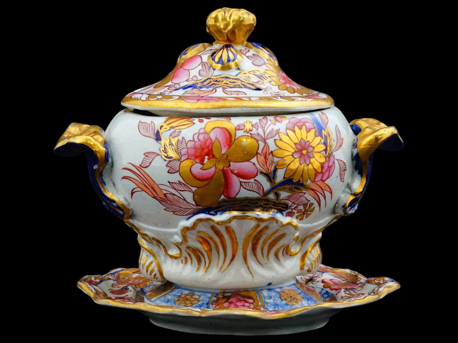 EARLY 19TH CEN ENGLISH PORCELAIN SAUCE TUREEN SET: An early 19th-century English porcelain sauce tureen set comprises a footed vessel, a domed cover with a notch for a ladle, and a matching scalloped stand. The exterior is decorated with finely