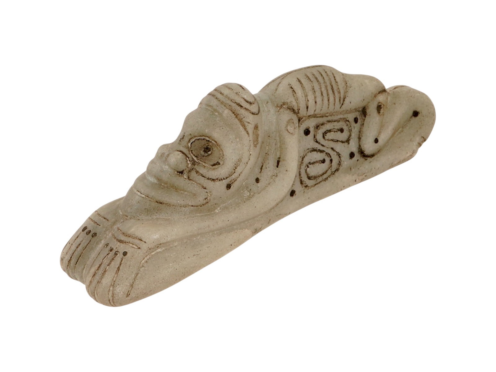 ANCIENT PRE COLUMBIAN TAINO CARVED STONE FIGURINE: An ancient Pre Columbian Taino hand carved stone figurine. The figurine depicts a recumbent figure with a highly stylized anthropomorphic face. The carving features prominent ocular orbits, a broad
