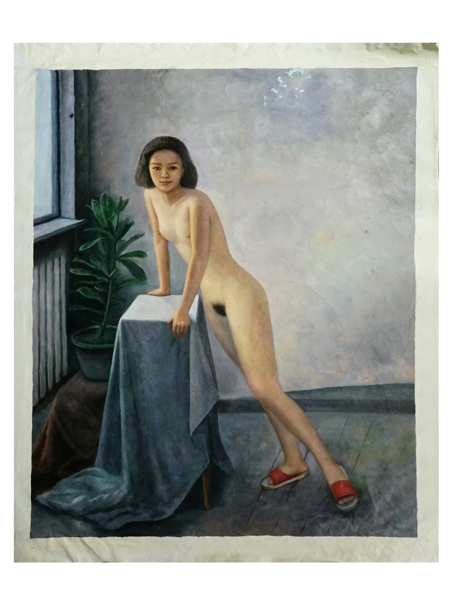 CHINESE FEMALE NUDE FIGURE OIL ON CANVAS PAINTING: An oil on canvas painting depicts a standing female nude figure in a realist interior setting, leaning against a pedestal draped with a deep blue textile. The subject is portrayed with short dark hair