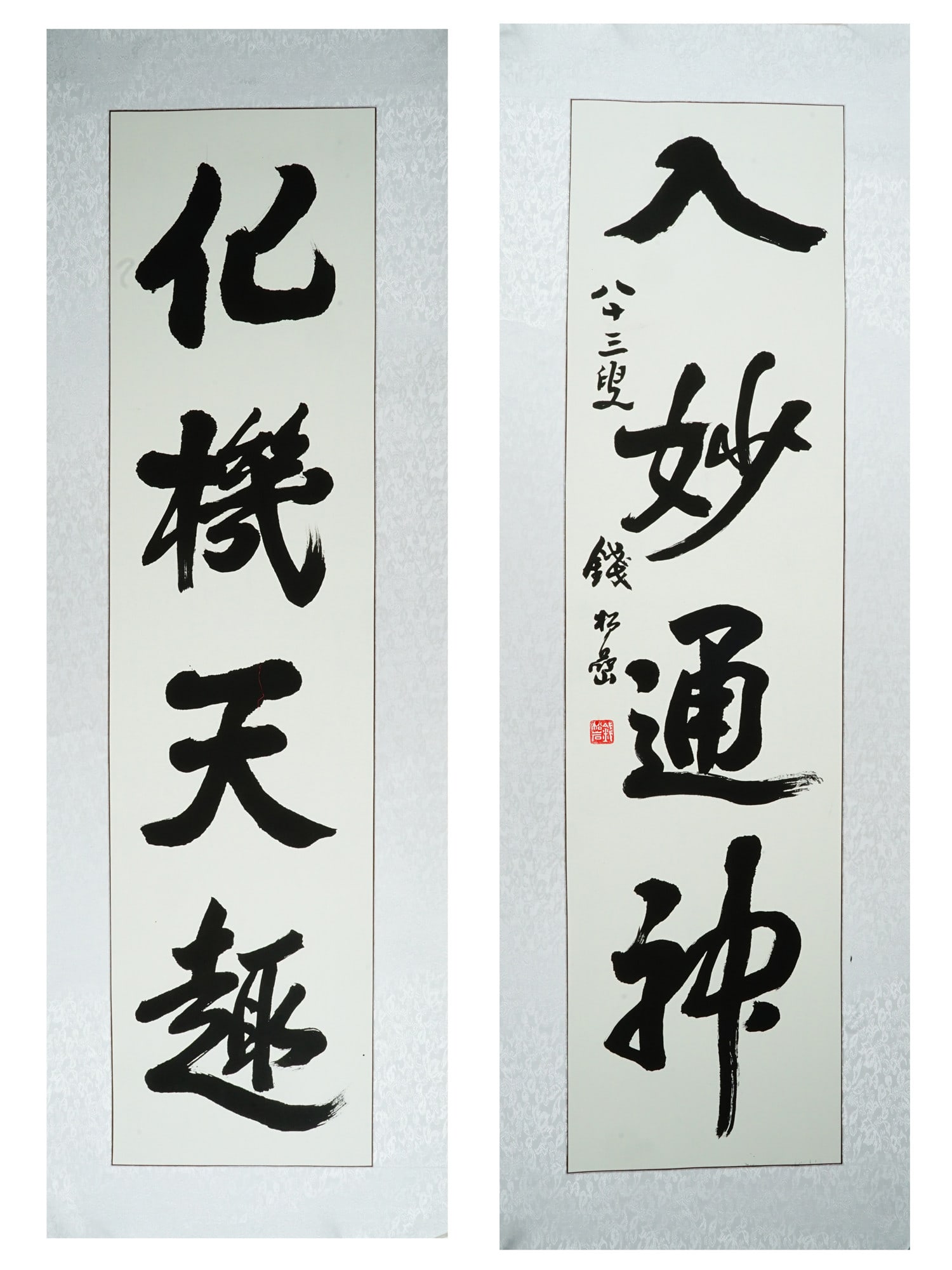 PAIR OF CHINESE INK CALLIGRAPHY SCROLLS: A pair of Chinese calligraphy scrolls is executed in black ink on paper, featuring a four-character poetic couplet rendered in bold, expressive cursive script. The right scroll includes a vertical col