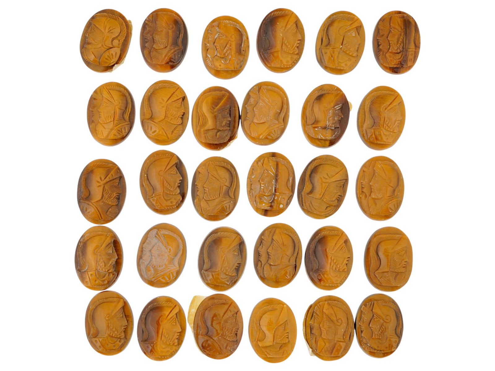 ANTIQUE OR VINTAGE CARVED TIGERS EYE STONE CAMEOS: A collection of 30 antique or vintage carved tigers eye stone cameos, depicting knight profiles in armor rendered in raised relief. The pieces display the gemstones characteristic golden-brown