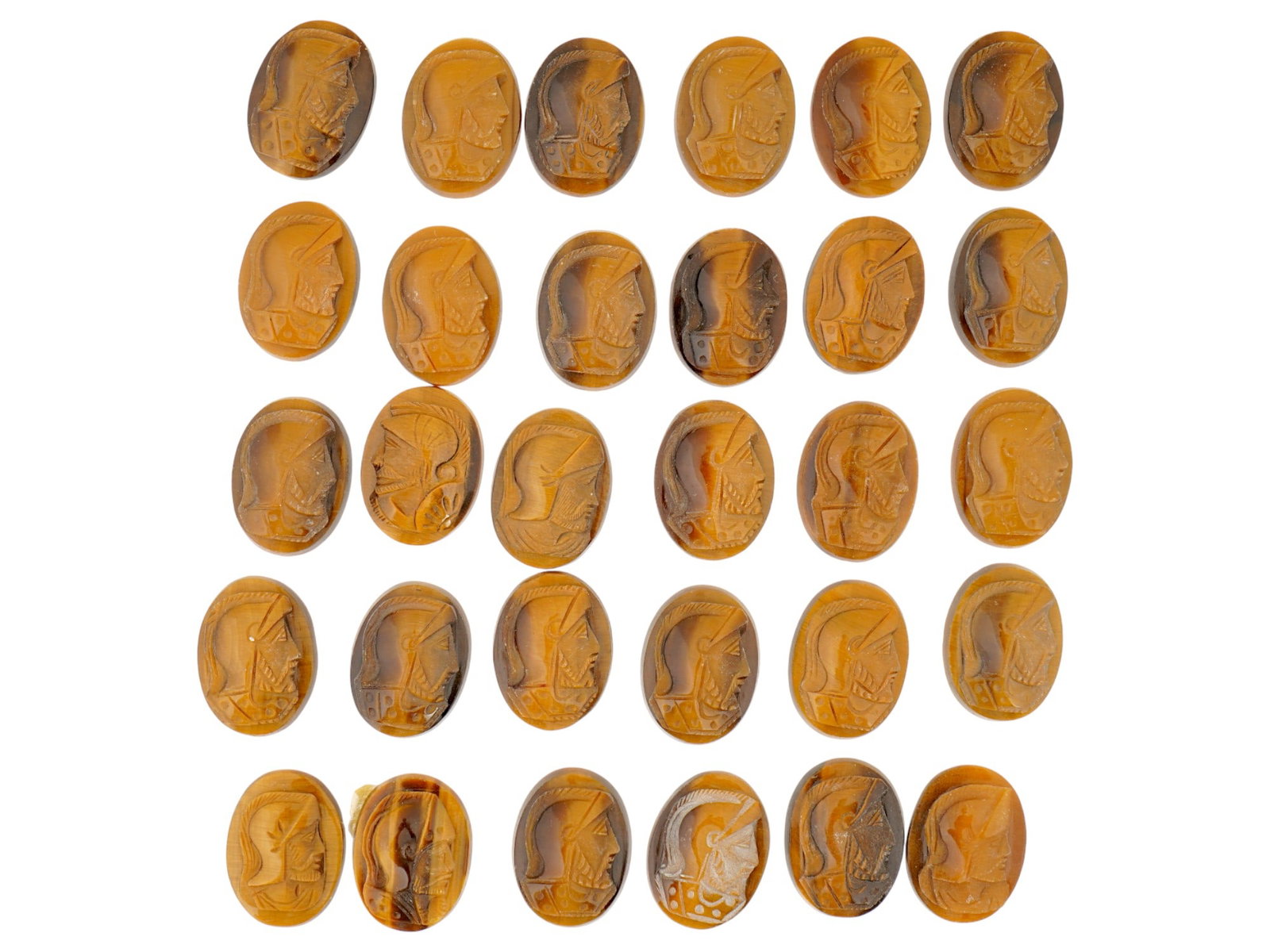 COLLECTION OF 30 CARVED NATURAL TIGERS EYE STONE CAMEOS: A collection of 30 hand carved natural tigers eye stone cameos. The cameos depict a Roman or Greek soldiers profile bust. The cameos are formed as small oval shaped medallions, intended for use in