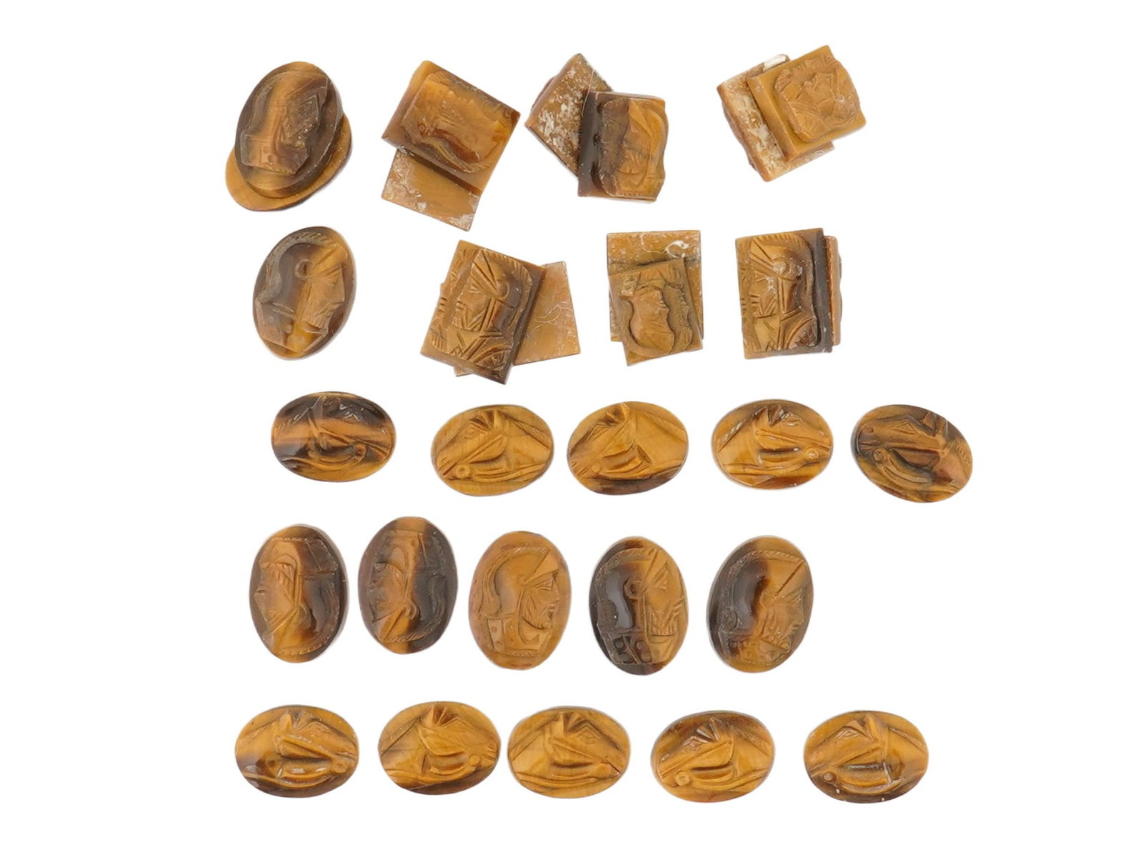 COLLECTION OF 30 CARVED NATURAL TIGERS EYE STONE CAMEOS: A collection of 30 hand carved natural tigers eye stone cameos. The cameos primarily depict a Roman or Greek soldiers profile bust, and some show a horses head. The cameos are formed as small rectangu