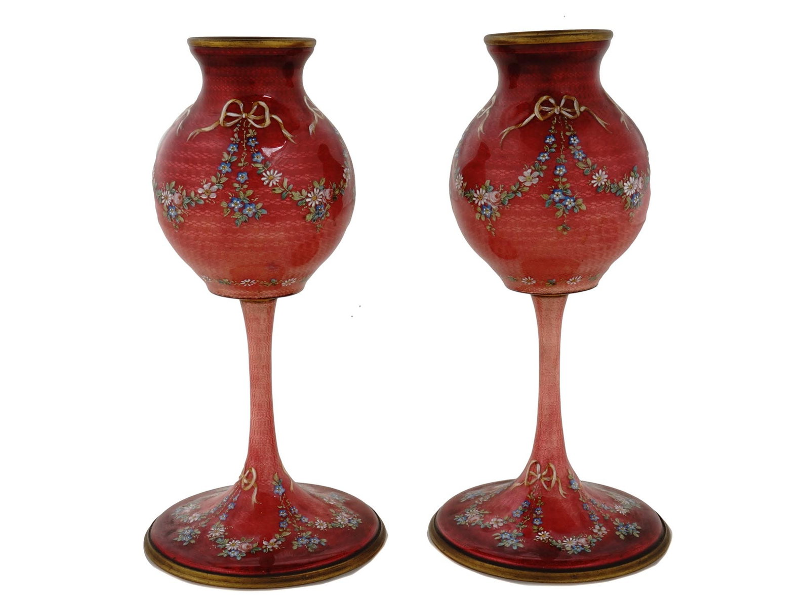PAIR OF RARE FOOTED RED GUILLOCHE ENAMEL VASES: A pair of rare vintage enameled brass vases. Each vase is mounted on a long foot. The exterior of the vases are covered with a Guilloche enamel in a red shade and adorned with floral and bows patterns