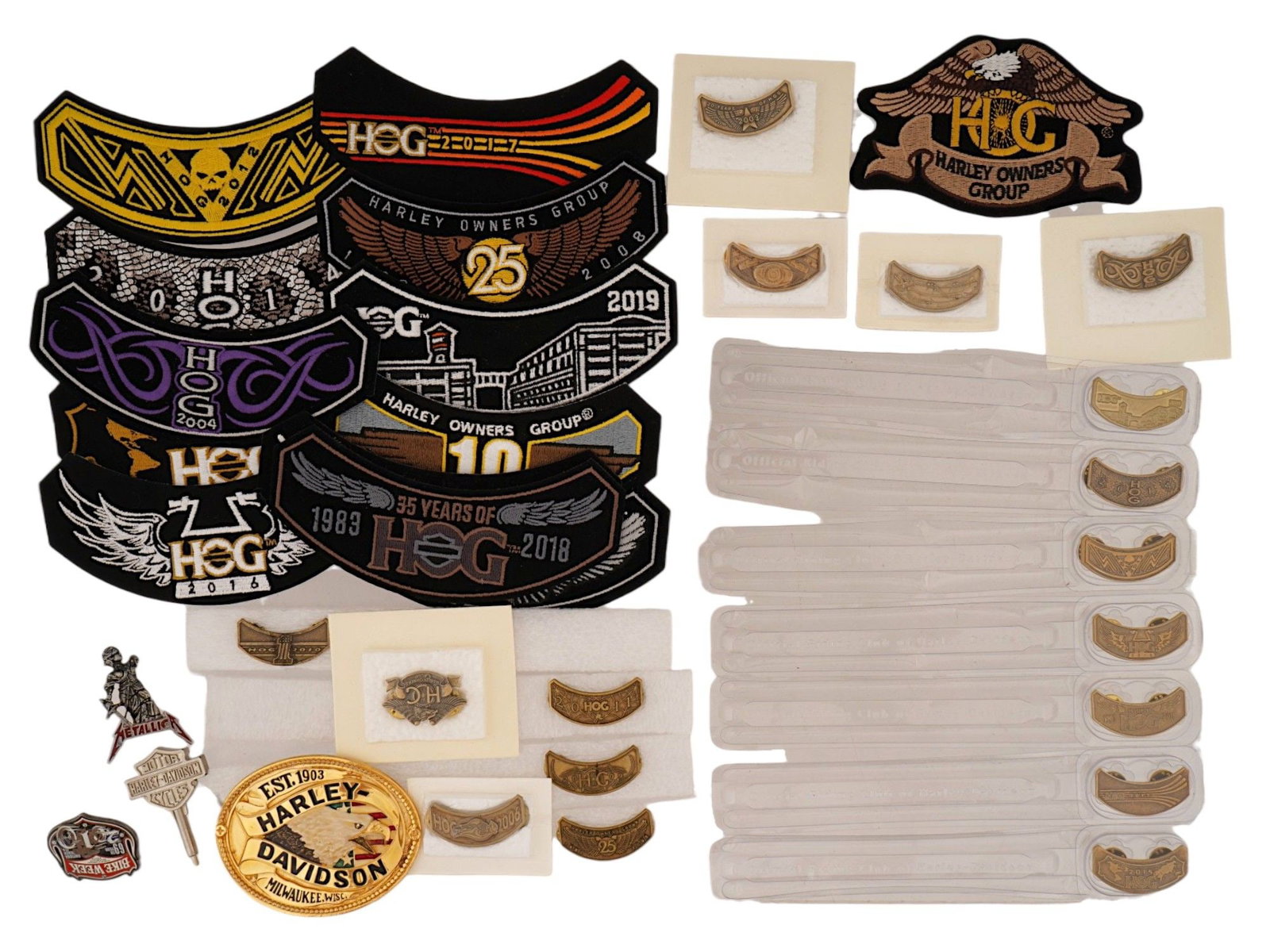 LOT OF ASSORTED HARLEY DAVIDSON MEMORABILIA ITEMS: A collection of Harley-Davidson Owners Group H.O.G. memorabilia includes a substantial assortment of embroidered rocker patches, an oval brass tone belt buckle, and several metal lapel pins. The patch