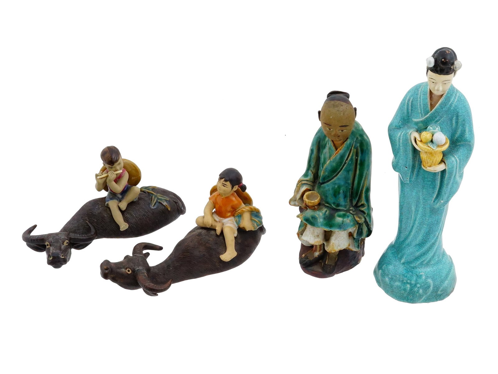 GROUP OF FOUR CHINESE GLAZED CERAMIC FIGURINES: A group of four Chinese glazed ceramic figurines includes two depictions of children riding water buffalo, a seated man in a green robe, and a standing female figure in a turquoise gown holding a flor