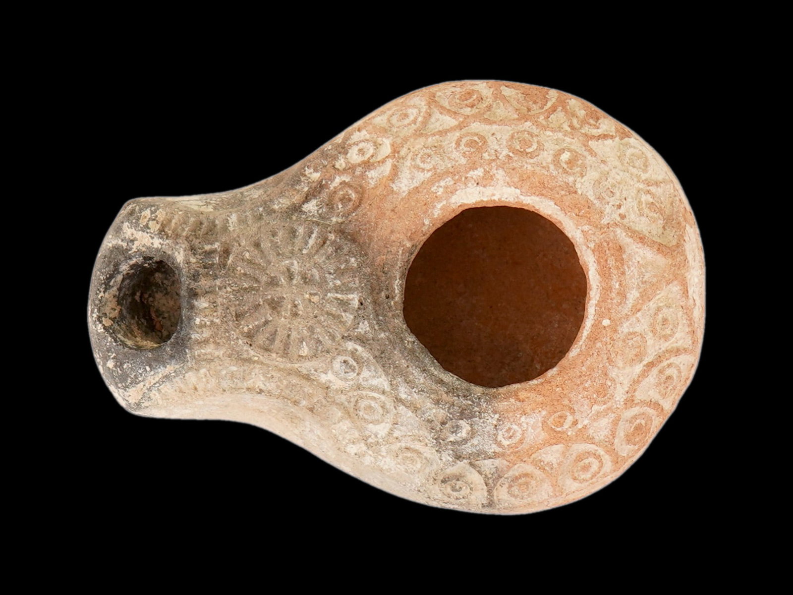 ANCIENT SAMARITAN JUDAICA TERRACOTTA POTTERY OIL LAMP: An ancient Samaritan Judaica moulded terracotta pottery oil lamp, known as a slipper lamp. The body of the lamp is hand painted and adorned with engraved ornaments. Lamps such as this one are occasion
