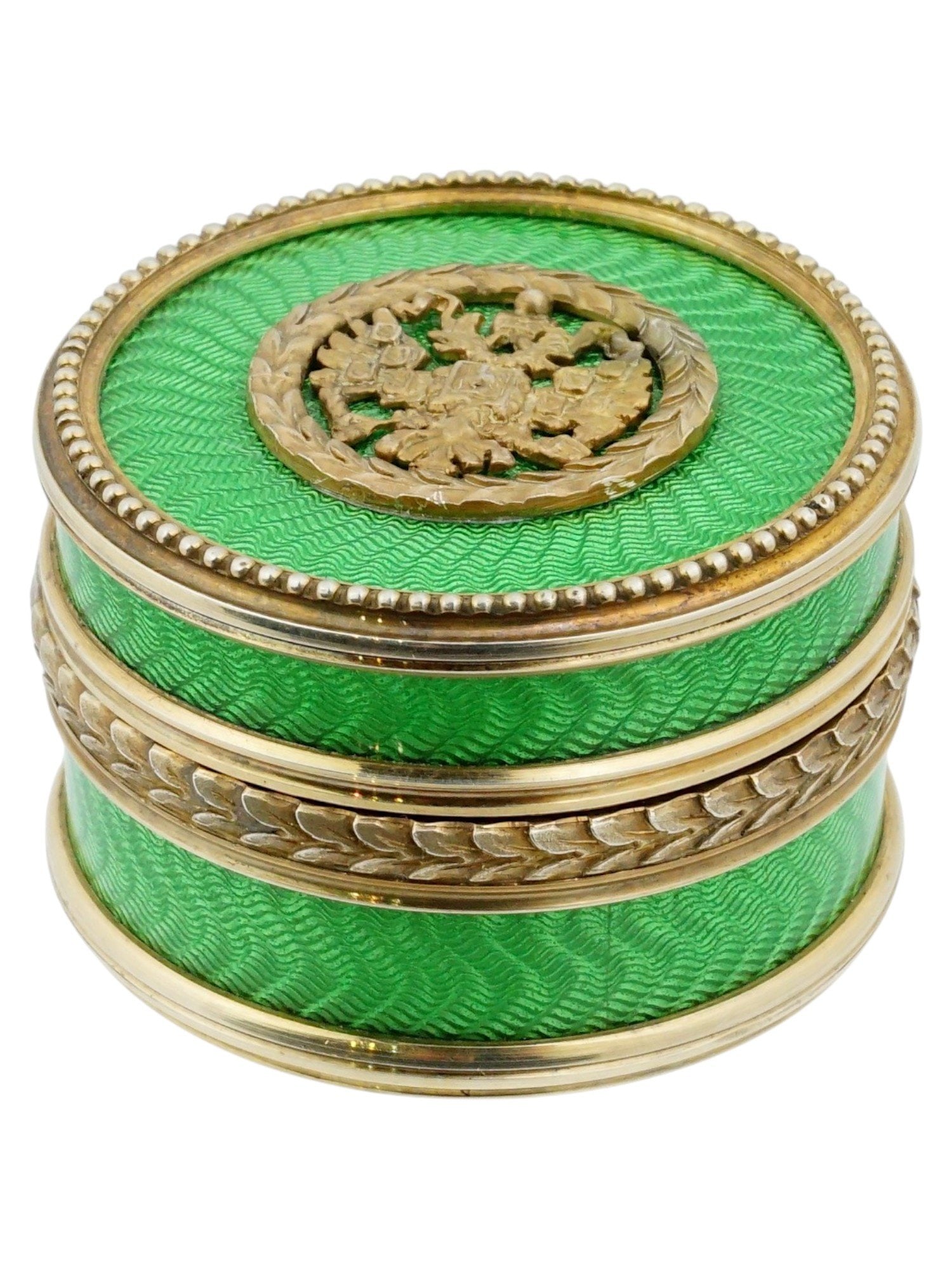 RUSSIAN IMPERIAL EAGLE SILVER AND ENAMEL PILL BOX: A Russian 84 Silver circular shaped pill box. The box is covered with green enamel over a sunburst guilloche engineturned ground. The detachable lid is ornamented with a central applied medallion