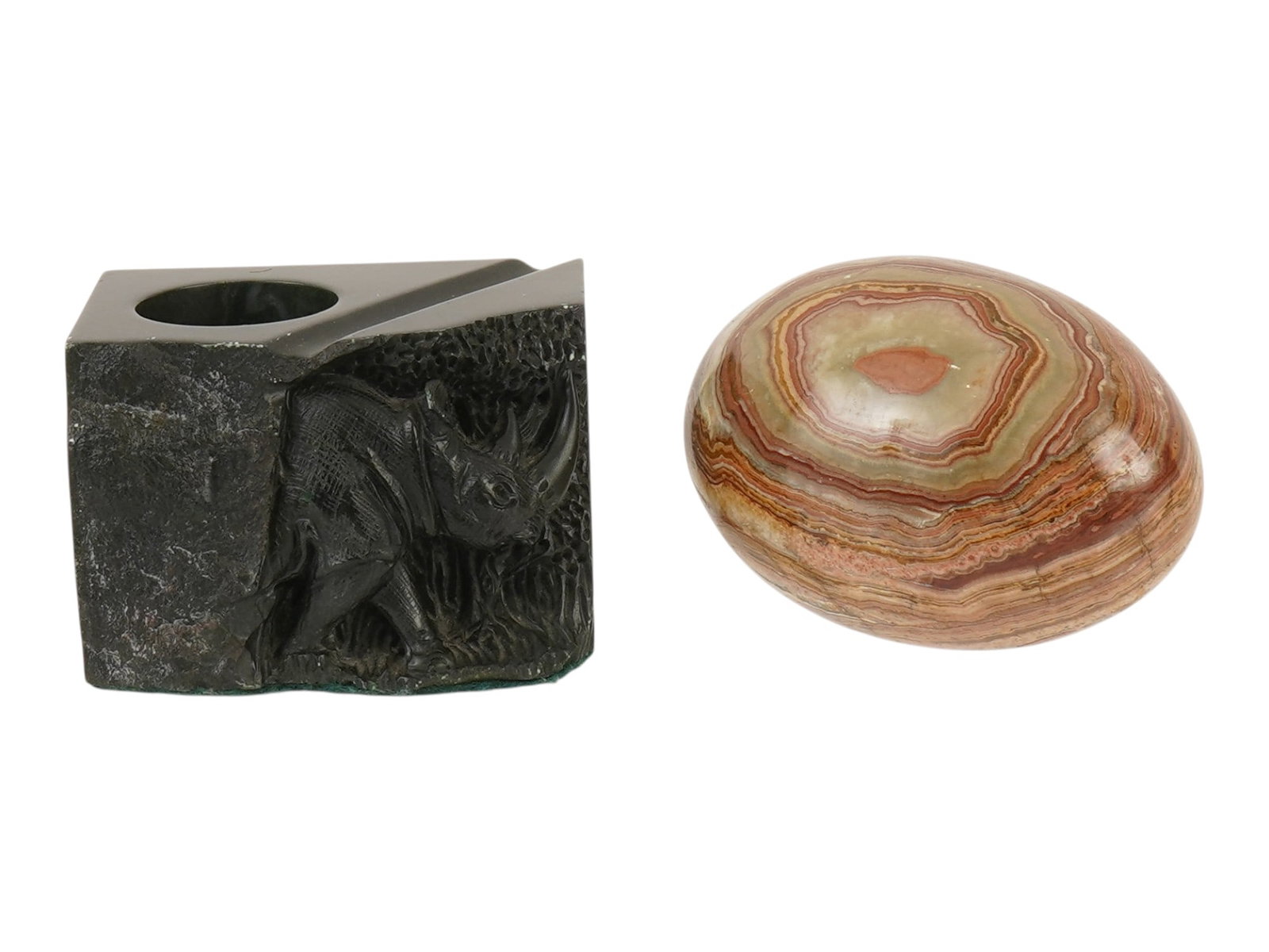 CARVED STONE TABLETOP ACCESSORIES RHINO STAND AND EGG: A lot of two vintage carved stone decorative tabletop accessories. This lot includes a stand or inkwell with a realistically carved rhinoceros and a marked Stoffel Phallane on the side. Also included