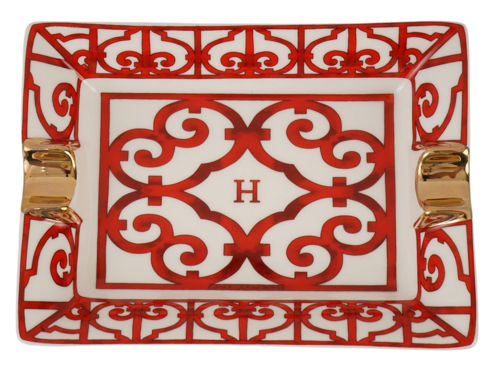 HERMES BALCON DU GUADALQUIVIR PORCELAIN ASHTRAY: A vintage porcelain ashtray by Hermes. Rectangular piece with two gilt cigarette holders and transfer-printed Balcon du Guadalquivir decoration. This flamboyant red piece pays homage to the bold
