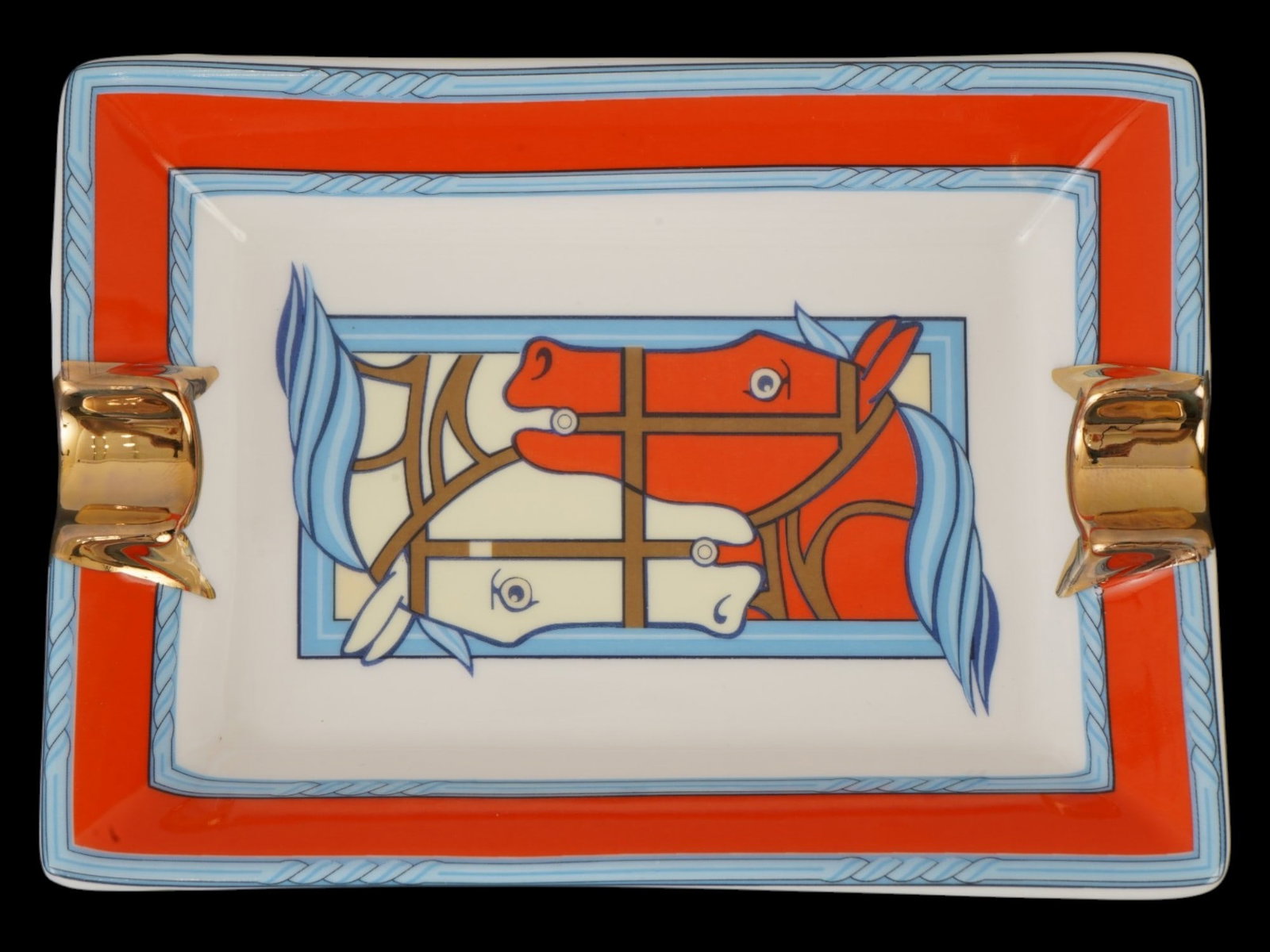 FRENCH HERMES QUADRIGE HORSE PORCELAIN ASHTRAY: A French Hermes Paris porcelain ashtray featuring the Quadrige horse print, designed by Pierre Peron in 1973. The piece is framed by a signature orange border and accented with gilt edged cigarette