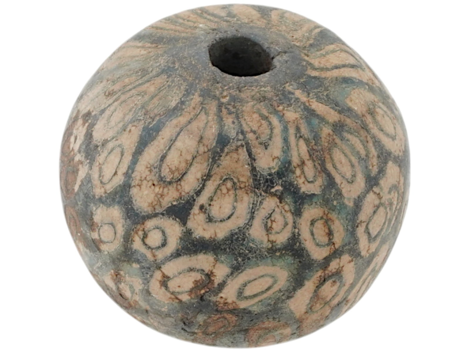 ANCIENT PHOENICIAN FUSED GLASS BEAD 500 TO 300 BC: An ancient Phoenician fused glass bead, circa 500 to 300 BC. The bead is spherical and has a relatively large hole drilled through the center. The glass has a multi layered design, with a dark bluish