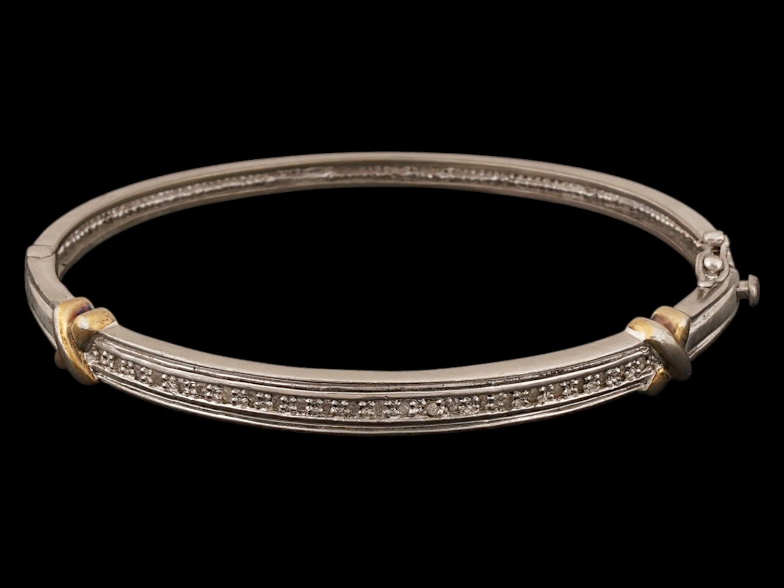 VINTAGE SILVER HINGED BRACELET WITH NATURAL DIAMONDS: A vintage sterling silver hinged cuff bracelet featuring a central row of channel-set round diamonds flanked by two gold-tone crossover accents. The piece is designed with a polished finish and a