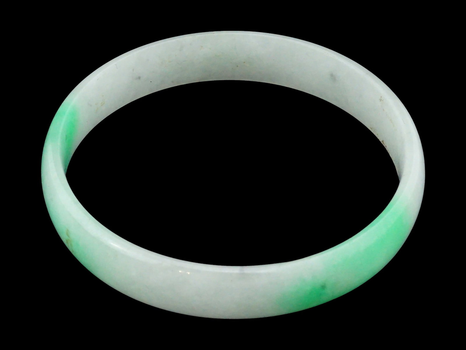 CHINESE CARVED JADE BABY BANGLE BRACELET: A Chinese jade baby bangle bracelet, carved in a classic round shape from a single piece of natural jade. The bracelet features smooth, polished surfaces and a graceful silhouette, highlighting the st