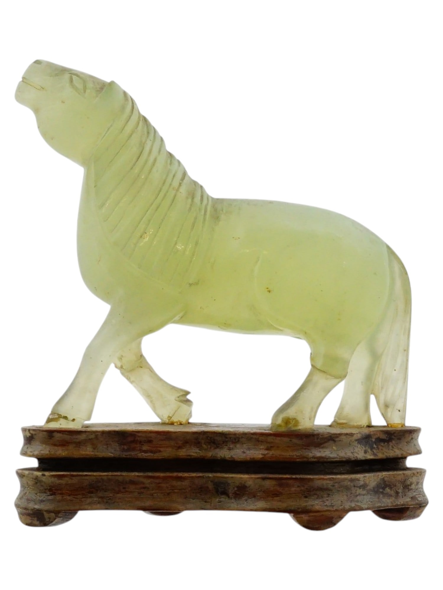 CHINESE HAND CARVED JADE HORSE FIGURINE ON WOOD BASE: A Chinese hand carved jade horse figurine on a wooden base. The equine figure is modeled in a spirited stance with a slightly raised head, featuring finely incised details to the mane and tail that de