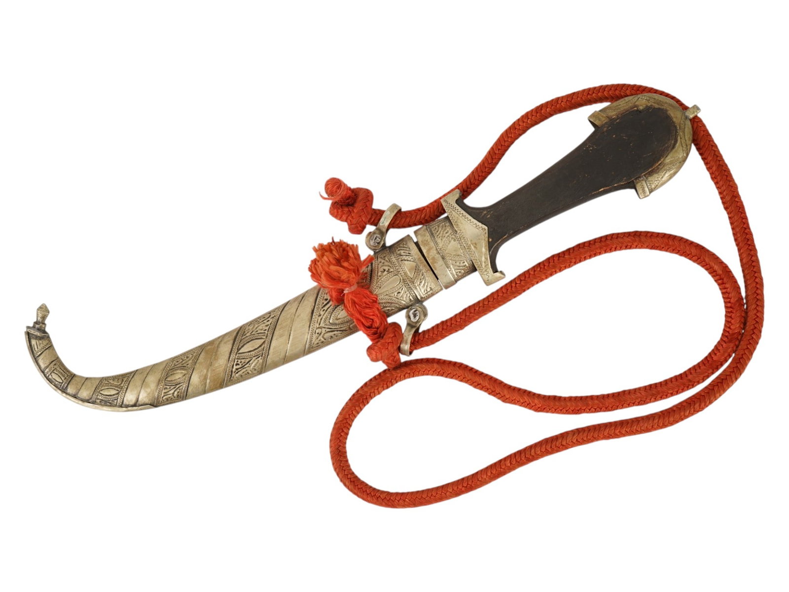TURKISH OTTOMAN EMPIRE KNIFE WITH SCABBARD RED CORD: A Turkish Ottoman Empire knife featuring a single edged, recurved steel blade housed within a chased metal scabbard decorated with traditional foliate and geometric motifs. The hilt is constructed