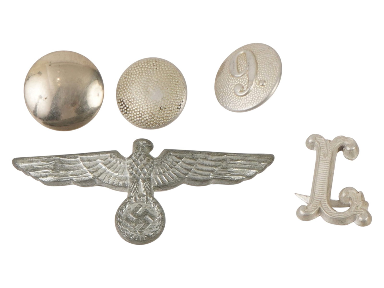 WWII TYPE NAZI GERMAN UNIFORM INSIGNIA AND FITTINGS: A collection of WWII type Nazi German military uniform insignia and fittings. The group includes a visor cap eagle, a metal shoulder board cipher, and several period uniform buttons of varying types. 