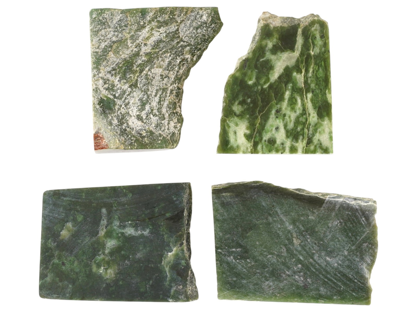 GROUP OF FOUR SIBERIAN GREEN JADE STONES: A group of four Siberian green jade stones. The stones display rich green tones with subtle inclusions and smooth surfaces, characteristic of jade sourced from Siberian regions. Valued for both