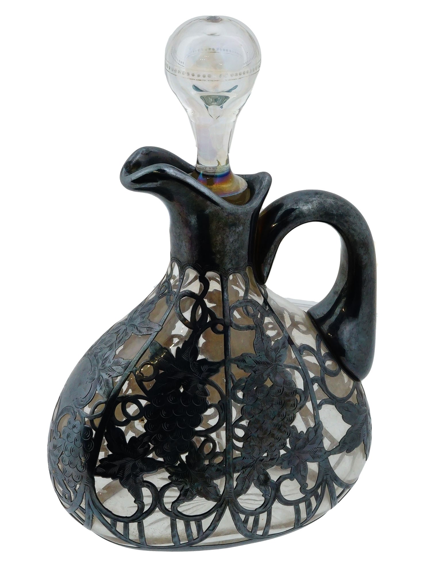 ANTIQUE ART NOUVEAU GLASS W SILVER OVERLAY DECANTER: An antique Art Nouveau cut glass with silver overlay decanter. The wide, flattened pear-shaped decanter with a side handle and an elongated spout. Decorated with a silver overlay featuring a
