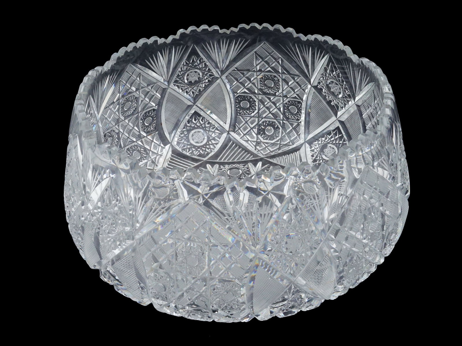 GEOMETRIC AND DIAMOND CUT DESIGN CRYSTAL GLASS BOWL: A circular bowl crafted from crystal glass. The exterior is intricately decorated with a program of deep geometric cuttings, featuring large multi point hobstars, fan motifs, and fine diamond cross ha
