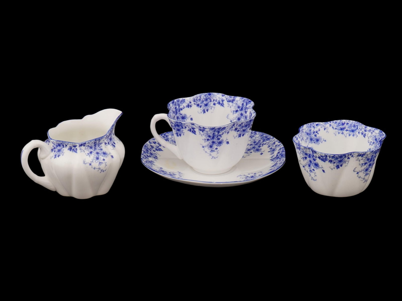 VINTAGE ENGLISH SHELLEY DAINTY BLUE PORCELAIN PIECES: Four vintage English porcelain pieces from a Shelley Dainty Blue set, including a creamer, bowl, and cup with a saucer, crafted in fine bone china. Produced by Shelley, the Dainty Blue pattern is