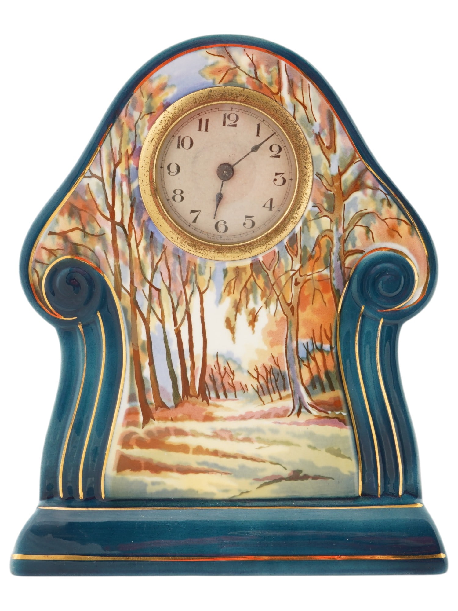VINTAGE GERMAN HAND PAINTED CERAMIC TABLE CLOCK: A vintage German hand painted ceramic table clock. The clocks flowing lines, inspired by Art Nouveau, are blue with gold accents. The front of the case is adorned with a hand-painted autumn forest