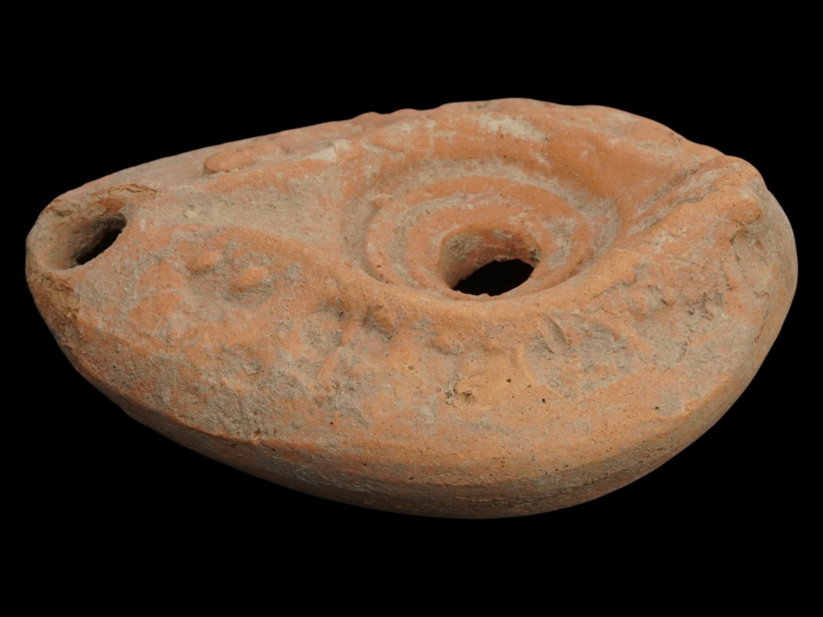 ANCIENT ROMAN TERRACOTTA OIL LAMP DESIGN 300 TO 400 AD: An ancient Late Roman terracotta pottery oil lamp. The body of the lamp is adorned with engraved ornaments on the shoulders. The lamp is decorated with a raised circle nozzle top. Circa: 300 to 400 AD