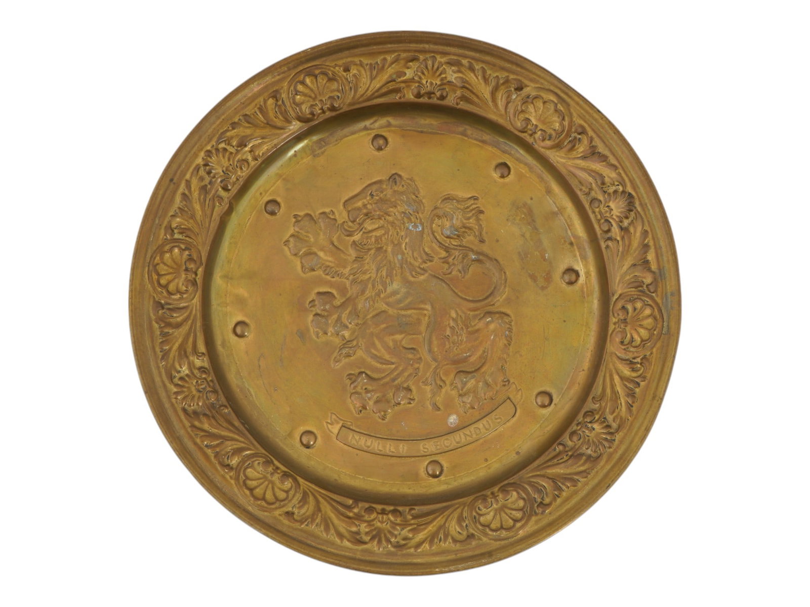 ROUND SHAPED LION MOTTO REPOUSSE BRASS WALL PLAQUE: A vintage round shaped repousse brass wall plaque. The plaque is adorned with a lion design in the center, and inscribed with the motto, Nulli Secundus meaning Second to None, lower to the center. Nul