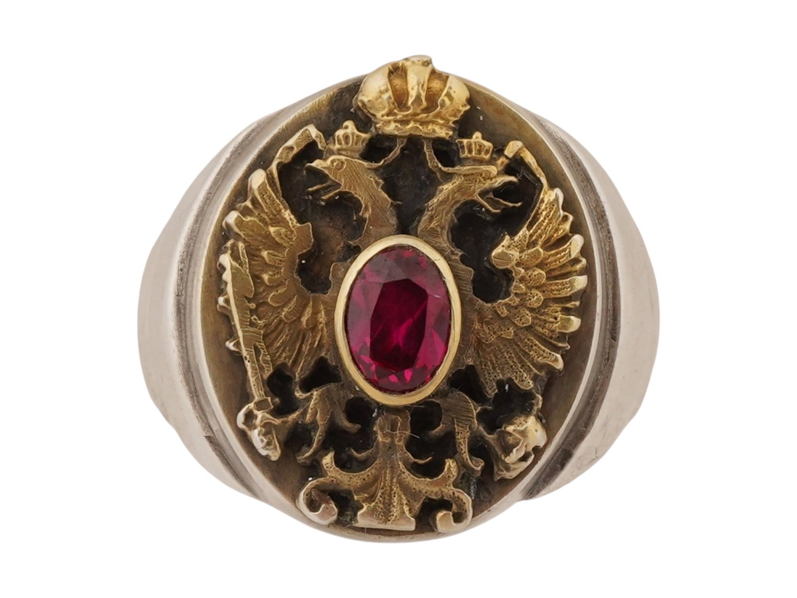 RUSSIAN IMPERIAL SILVER SIGNET RING WITH A RUBY STONE: A Russian Imperial silver signet ring featuring the Russian Imperial double-headed eagle beneath the Imperial Crown. The central motif is accented with a cut ruby stone set within a gilt mount at the 