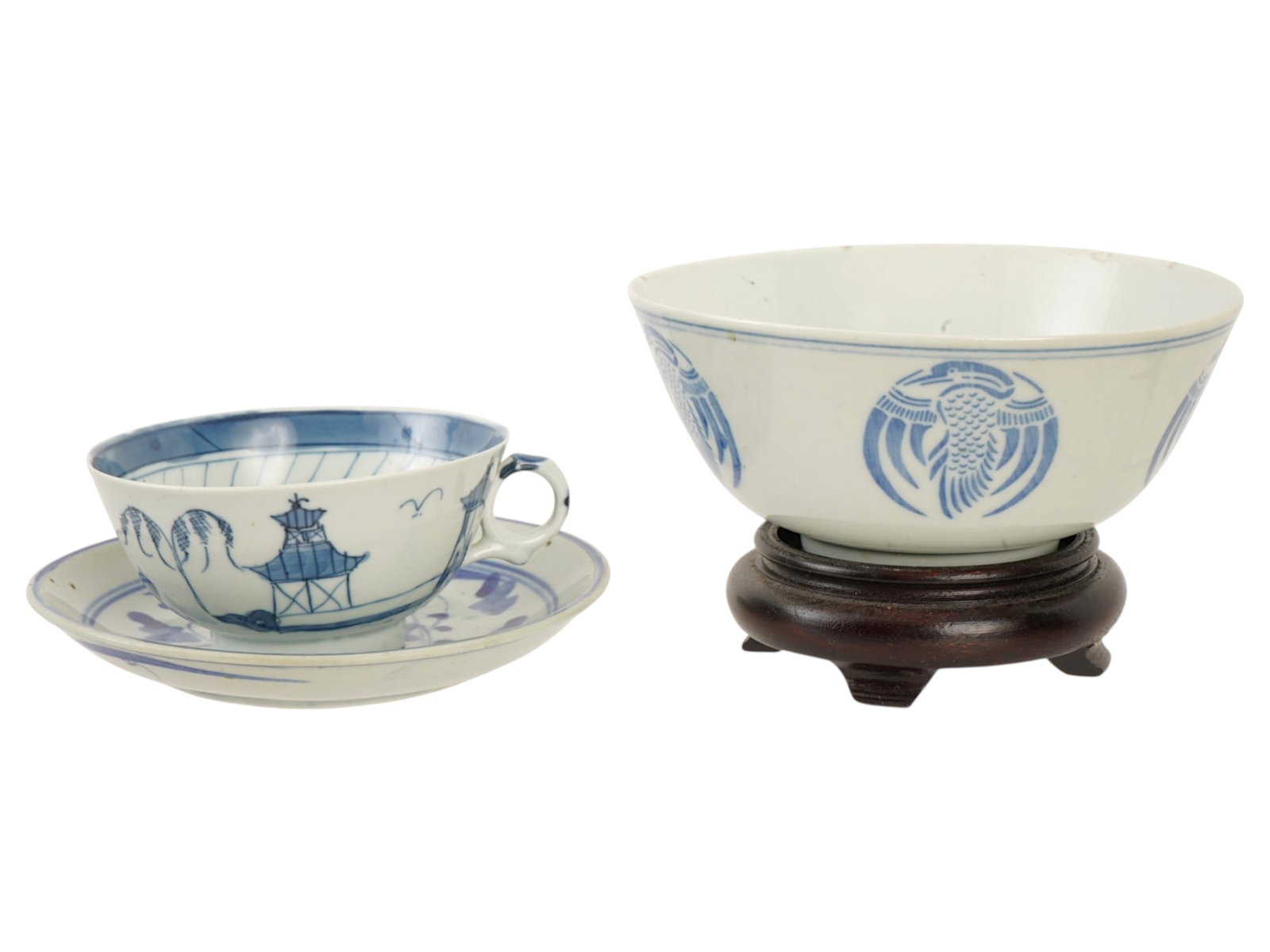 ANTIQUE CHINESE QING PORCELAIN WARES AND WOODEN STAND: A group of three antique Chinese Qing Dynasty blue and white porcelain wares including two tea cups, causer and a hand carved wooden stand. The first cup is adorned with a landscape image with a pagod