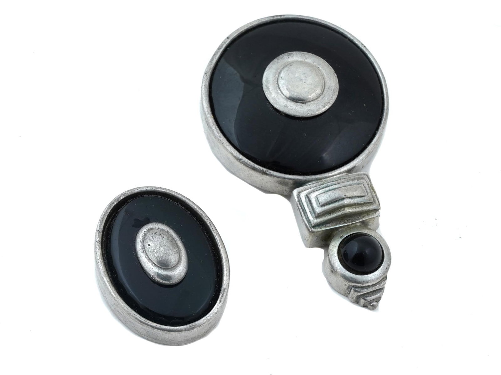 TWO VINTAGE BEN AMIN PIN BROOCHES CIRCA 1980S: A lot of two vintage Ben Amin pin brooches. Circa 1980s. The lot includes a Modernist manner oval and round silver tone brooches with black cabochon stones, marked verso Ben Amun. Vintage Fashionable 