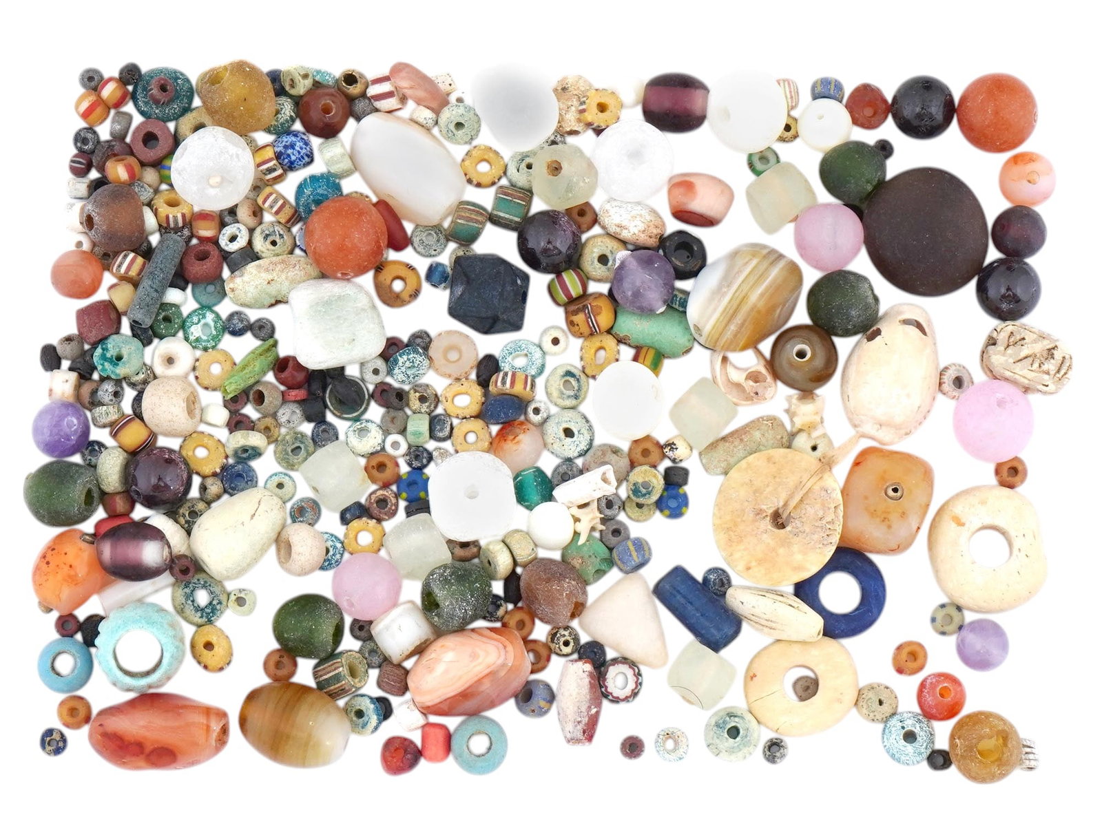 ANCIENT AMETHYST CORNELIAN AGATE GARNET GLASS BEADS: A large collection of various ancient beads made in various sizes and shapes. The collection includes beads made of Glass, Amethyst, Cornelian, Lapis Lazuli, Agate, Faience, Garnet, and other stones. 