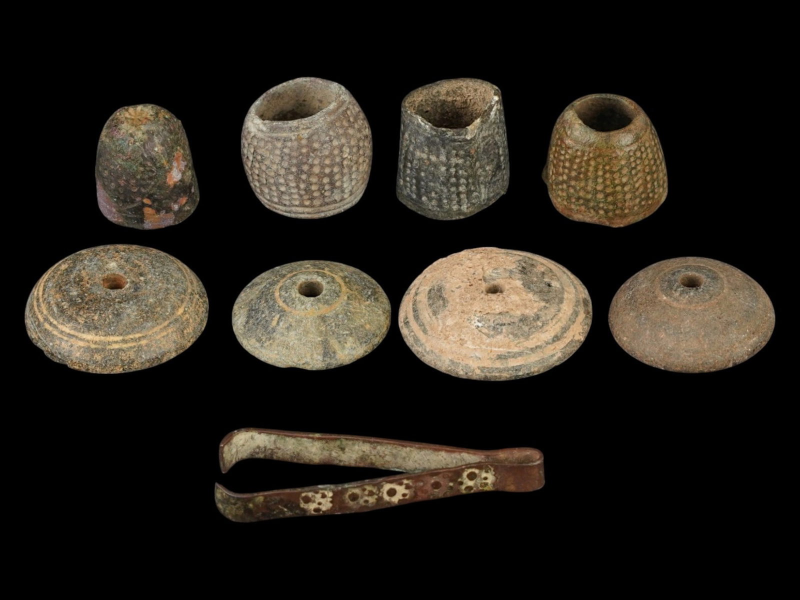 GROUP OF ANCIENT GRECO-ROMAN SEWING ACCESSORIES: A lot of Ancient Mediterranean sewing accessories, including bronze thimbles, a pair of bronze tweezers, and steatite spindle whorls. Greek or Roman origin, ca. 300 BC to 300 AD. A total of 9 pieces. 