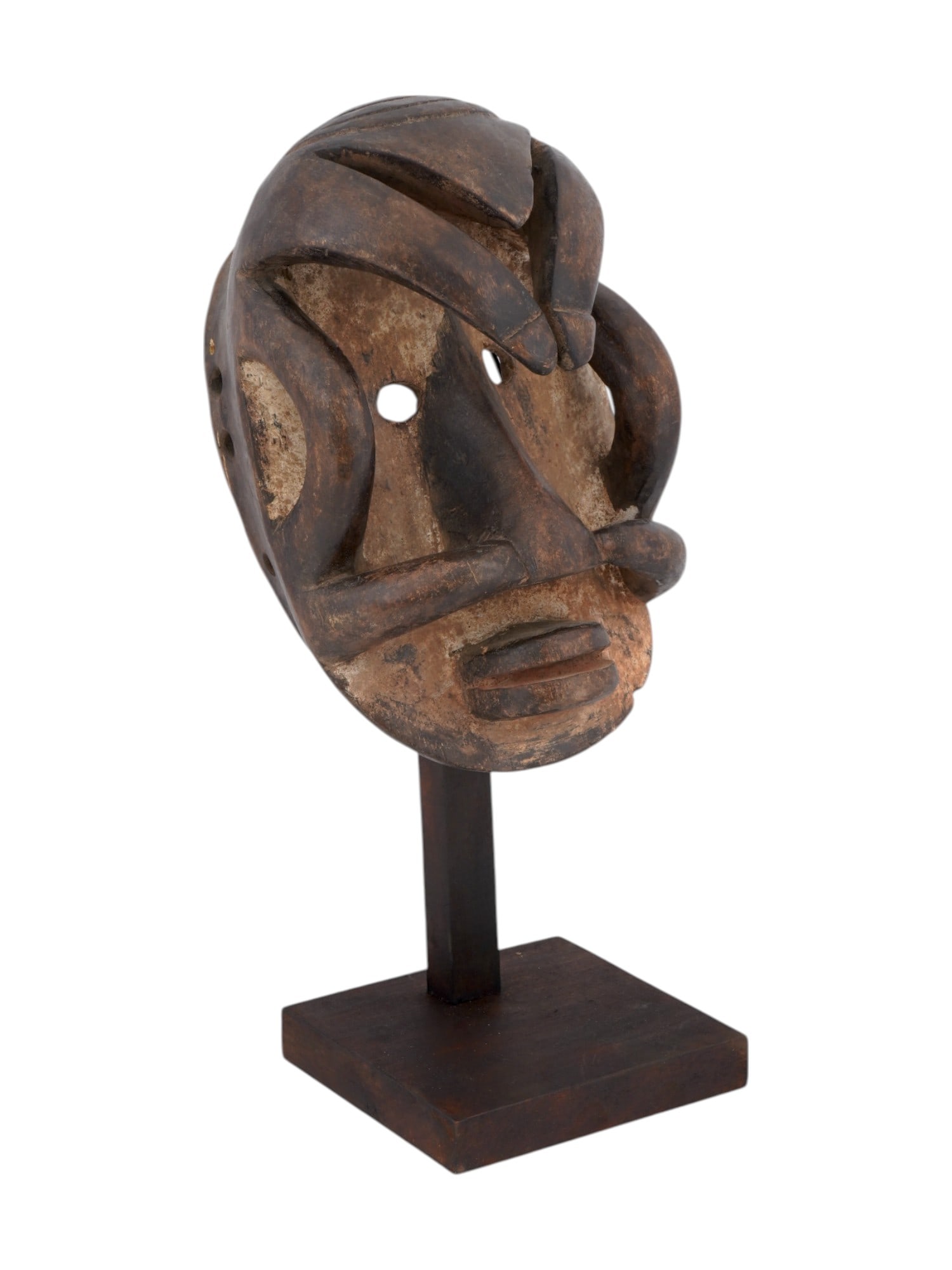 CENTRAL AFRICAN BAULE PEOPLE CARVED WOODEN MASK: A Central African Ivory Coast hand carved wooden mask of Baule people. The mask is a face with round holes for the eyes and skillfully crafted geometric shapes partially covering the face. Through hol