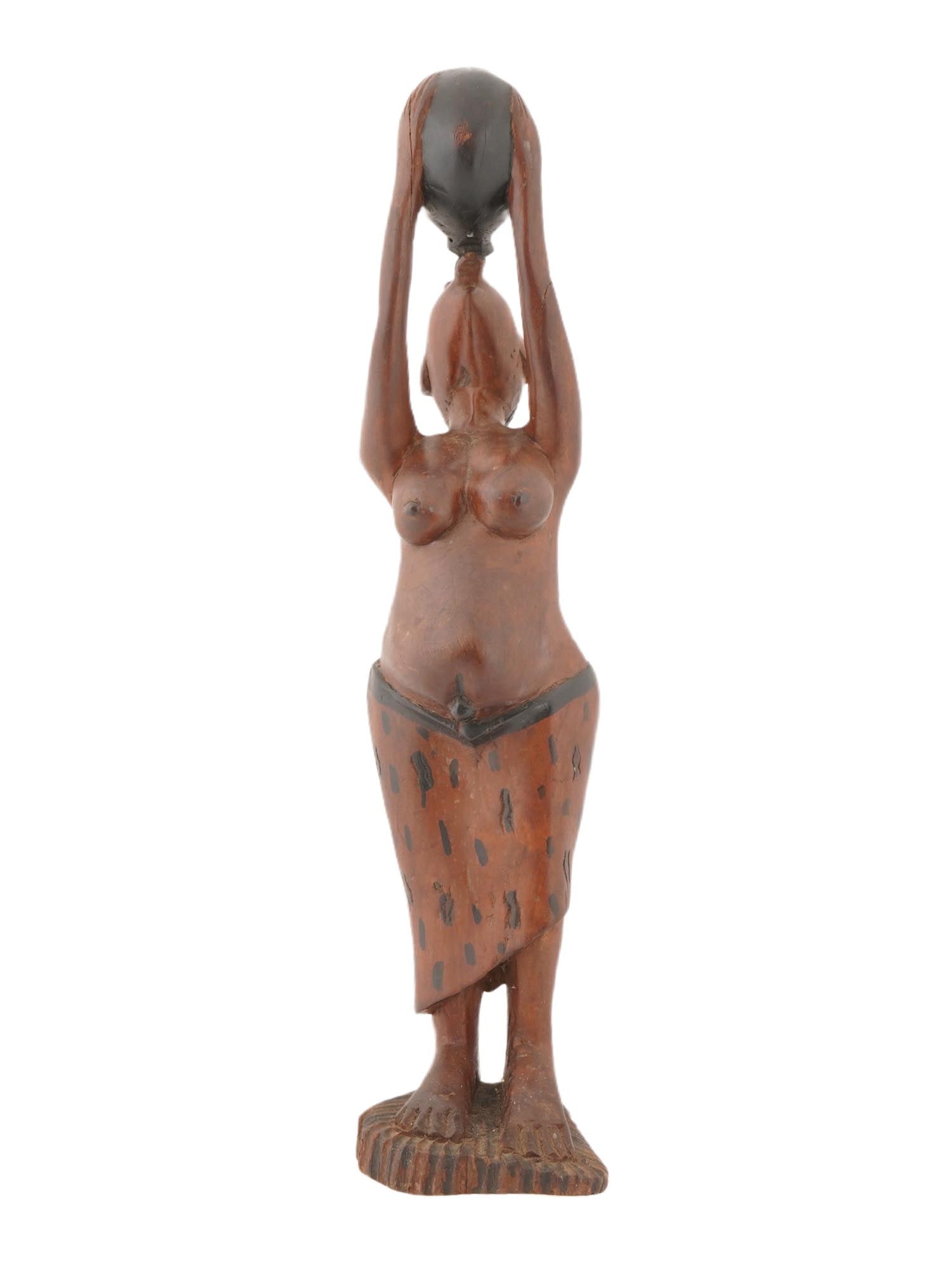 AFRICAN HAND CARVED WOODEN SCULPTURE OF WOMAN DRINKING: An African hand-carved wooden sculpture of a woman. The statue depicts a bare-breasted female figure with a detailed face and a distinct hairstyle, drinking water from a pot. These sculptures are a co