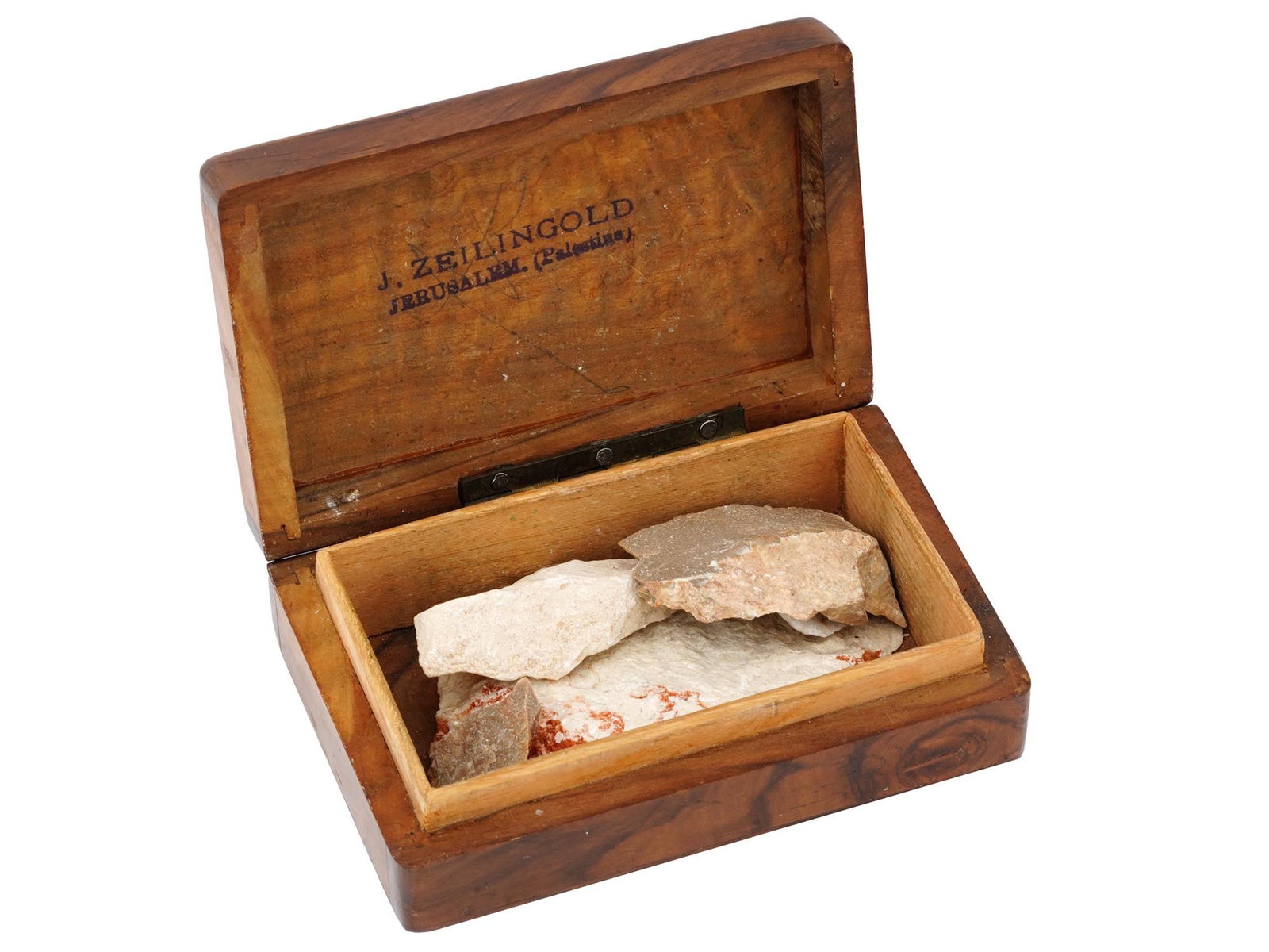 FIVE PIECES OF ROCK FROM JERUSALEM IN BOX: A wooden box containing five pieces of rock from Jerusalem. The rocks are of various shapes and sizes of a pale beige color with some reddish brown markings. One rock is hand marked: Jerusalem 10 84. 